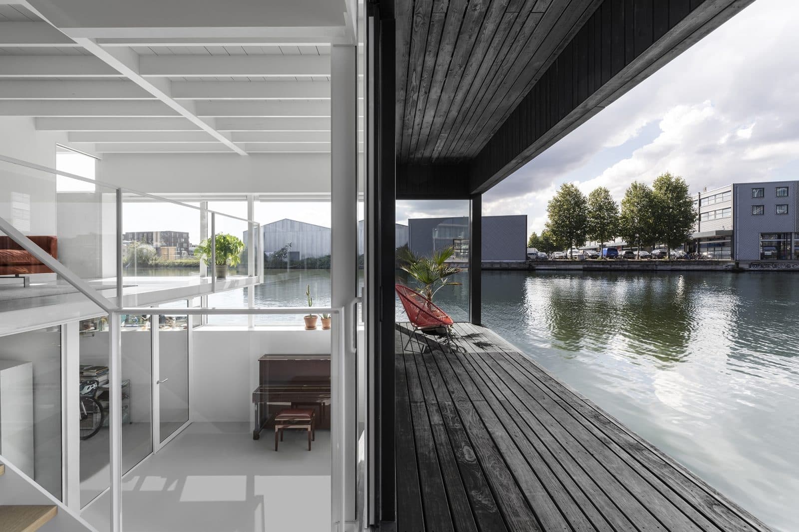 Zwart houten woonboot met glazen voorzijde aan kanaal