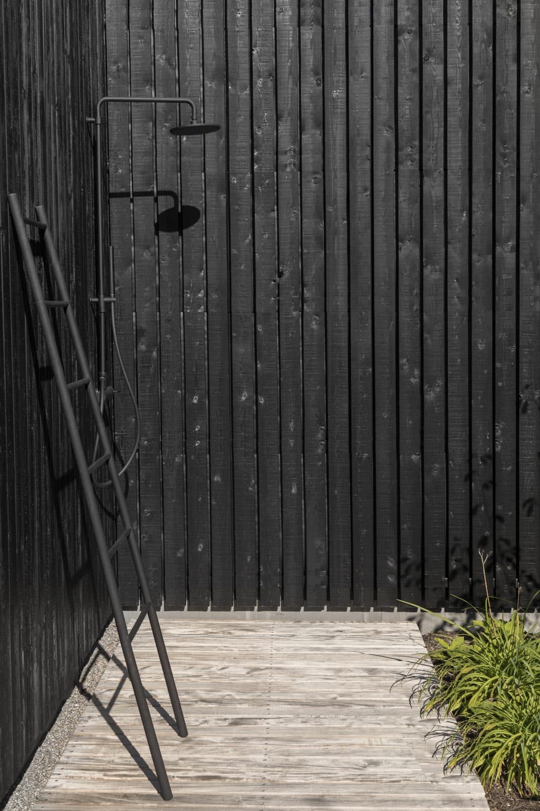 Donkere buitenwanden met minimalistisch zwart douchegedeelte op houten vloer