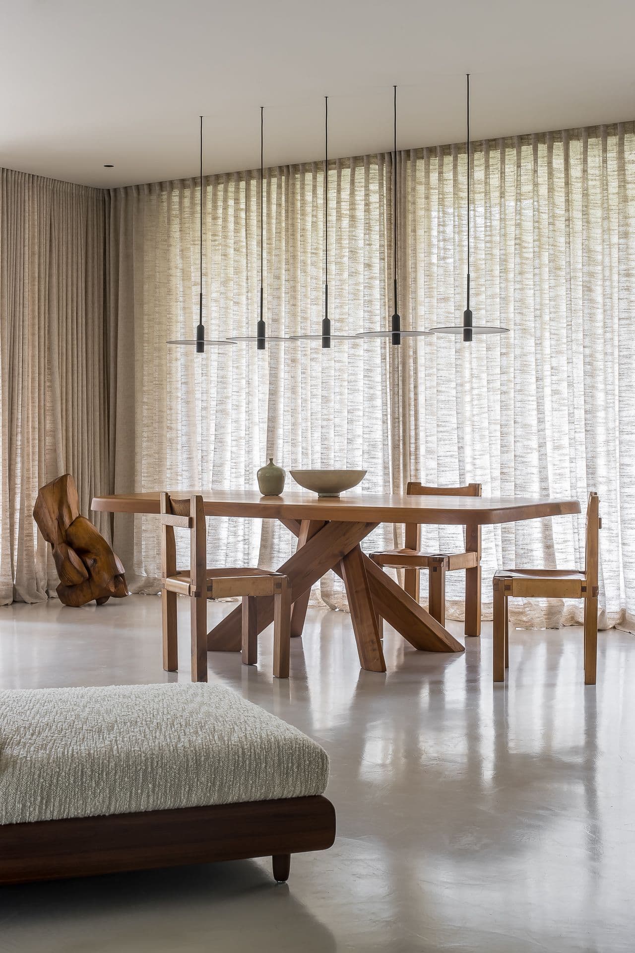 Eetkamer met houten tafel, stoelen en linnen gordijnen
