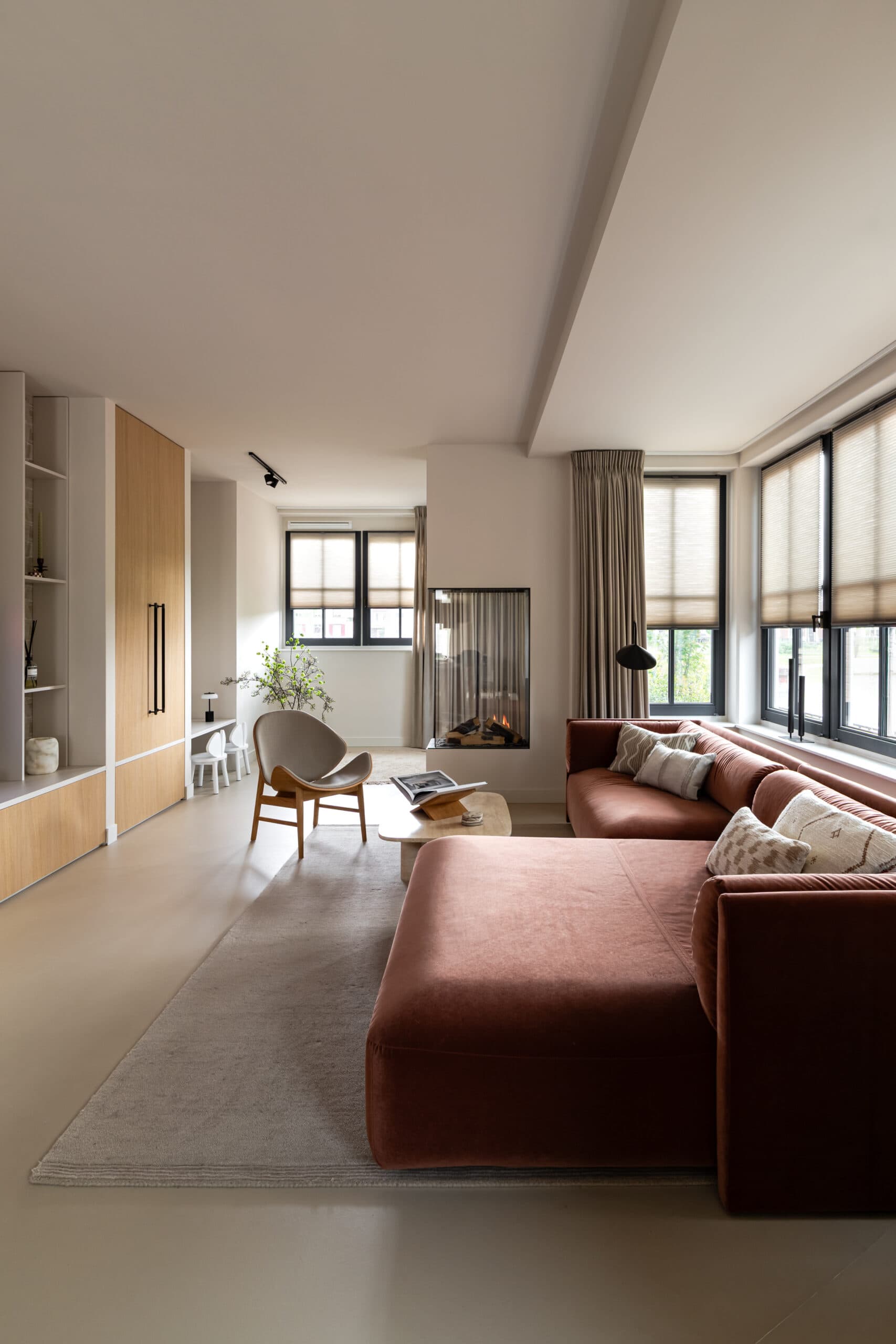 Woonkamer met glazen wand, houten stoelen en open haard