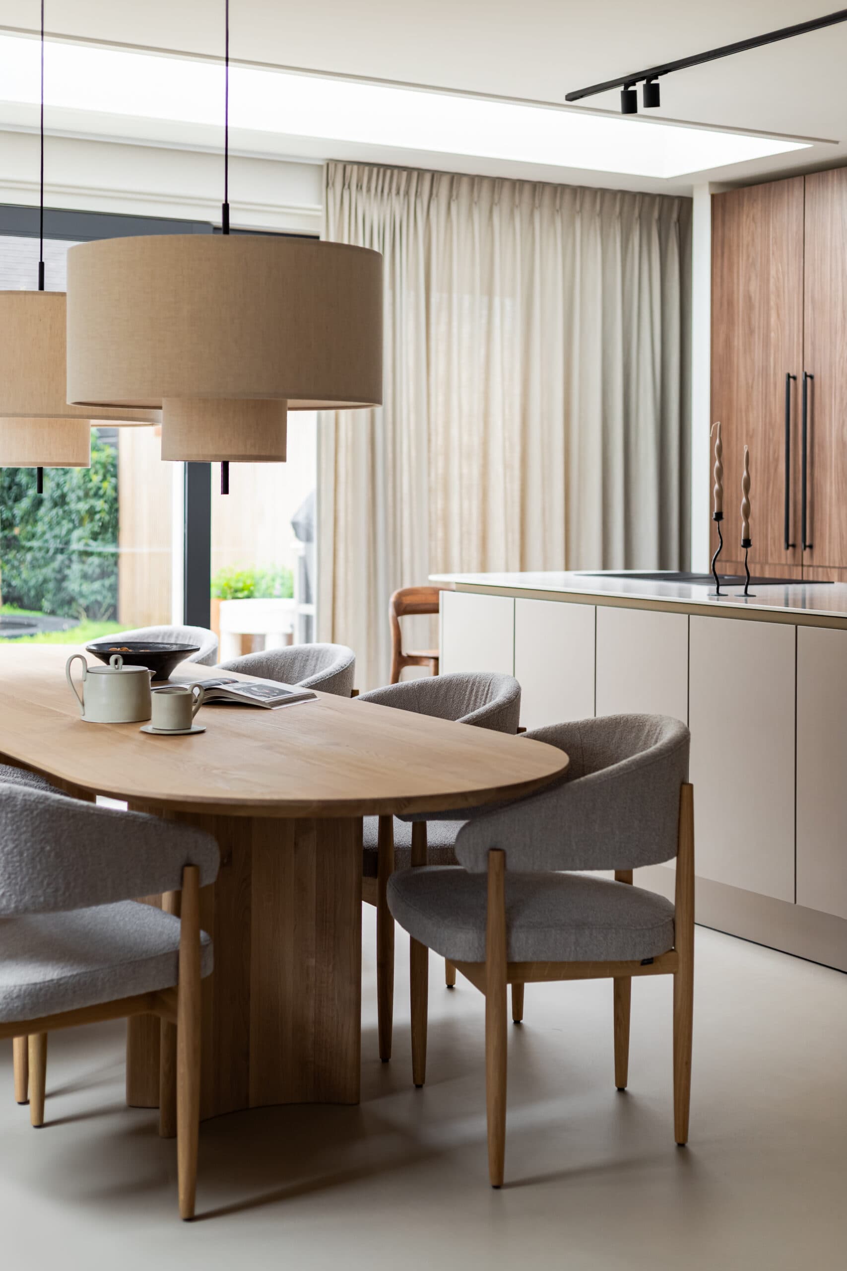 Eetkamer met ovaal houten tafel en grijze stoelen onder dakvenster
