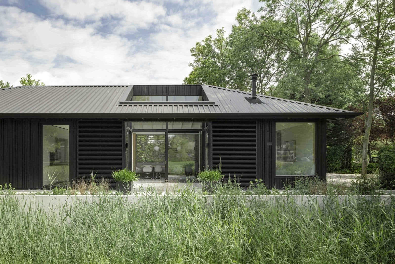Moderne zwarte woning met golfplaten gevel en groene heggen