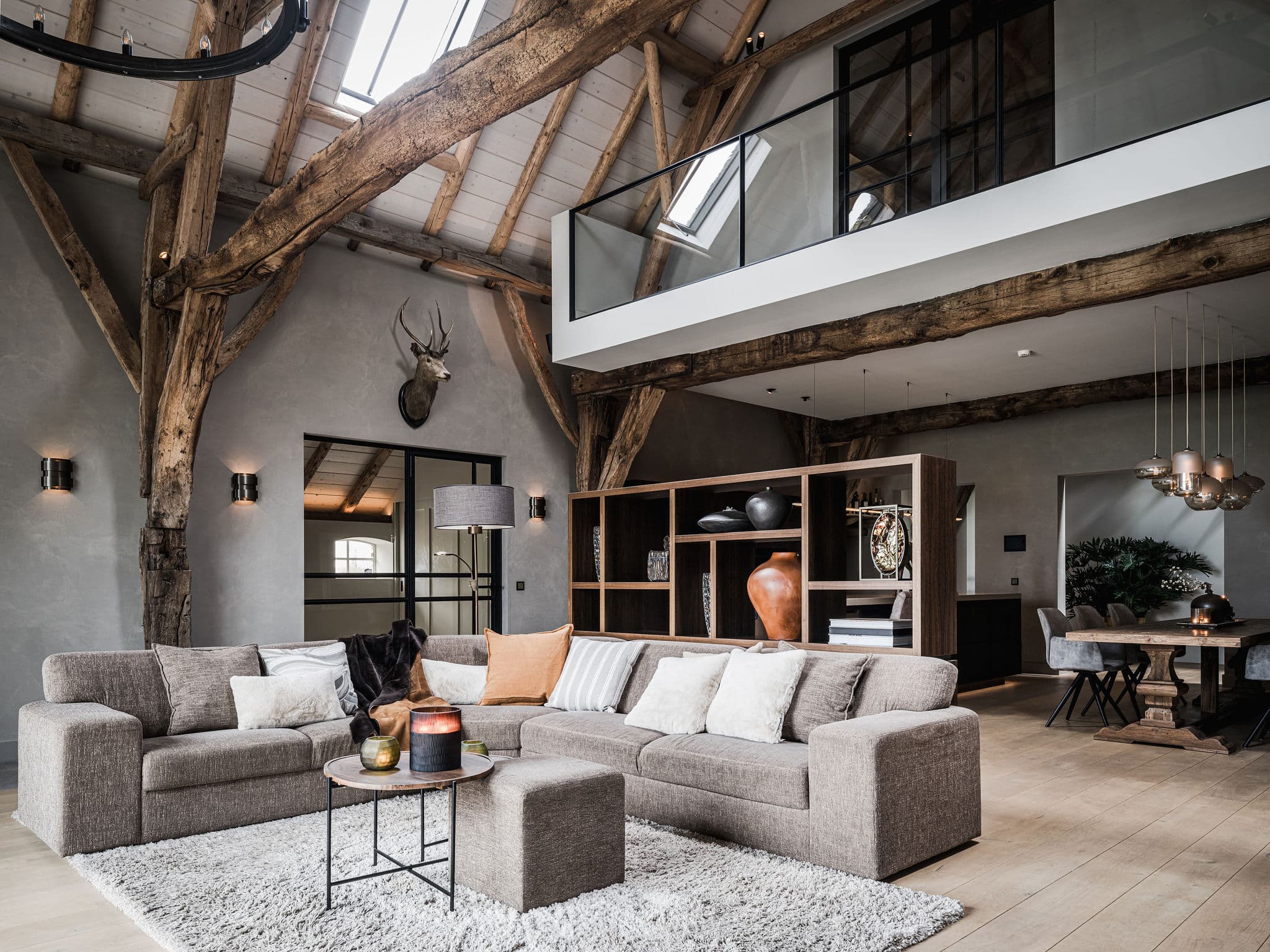 Dubbele woonkamer met houten balken, beige meubels en mezzanine