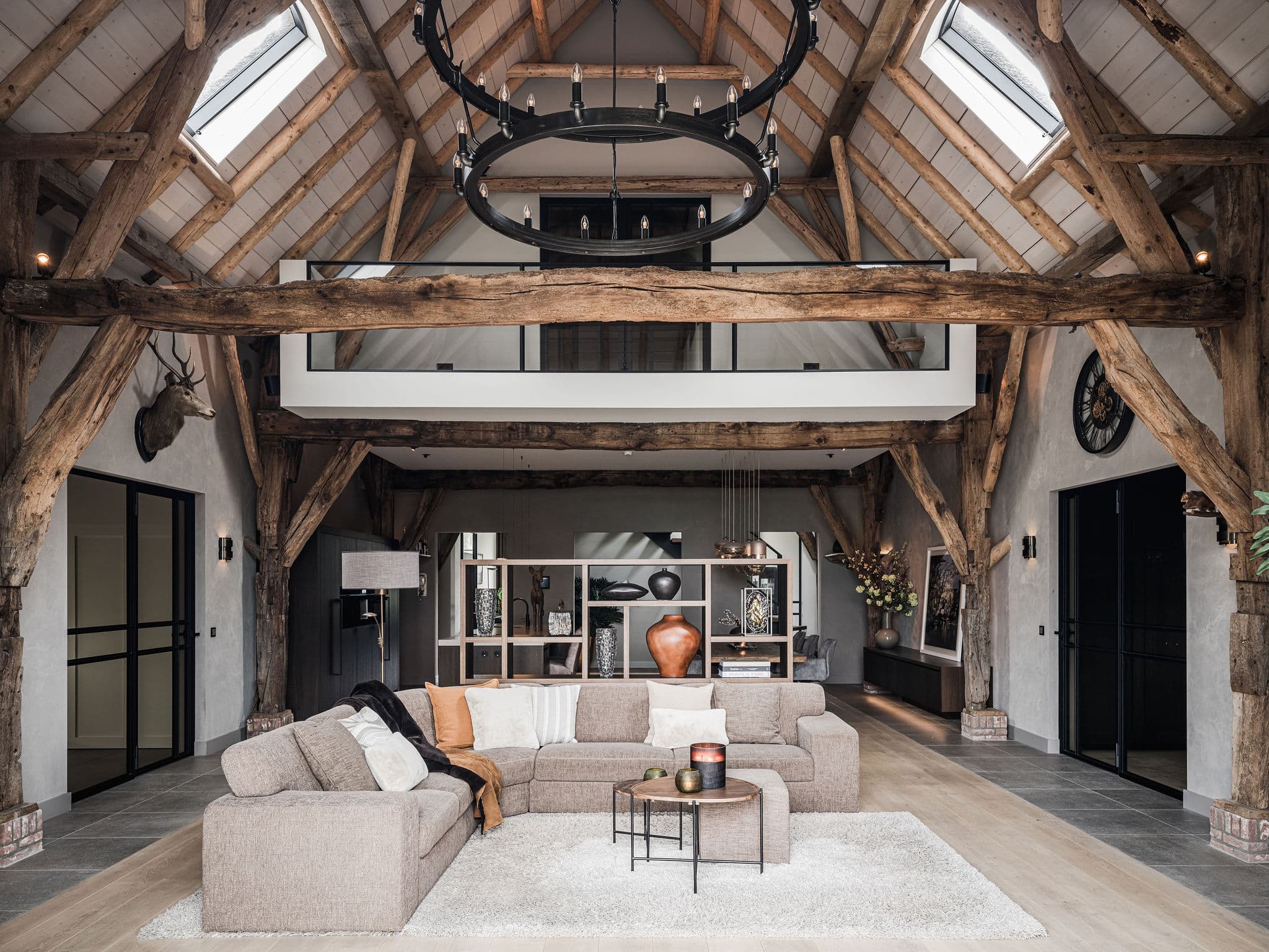 Woonkamer met houten spanten, beige loungebank en stalen hanglamp