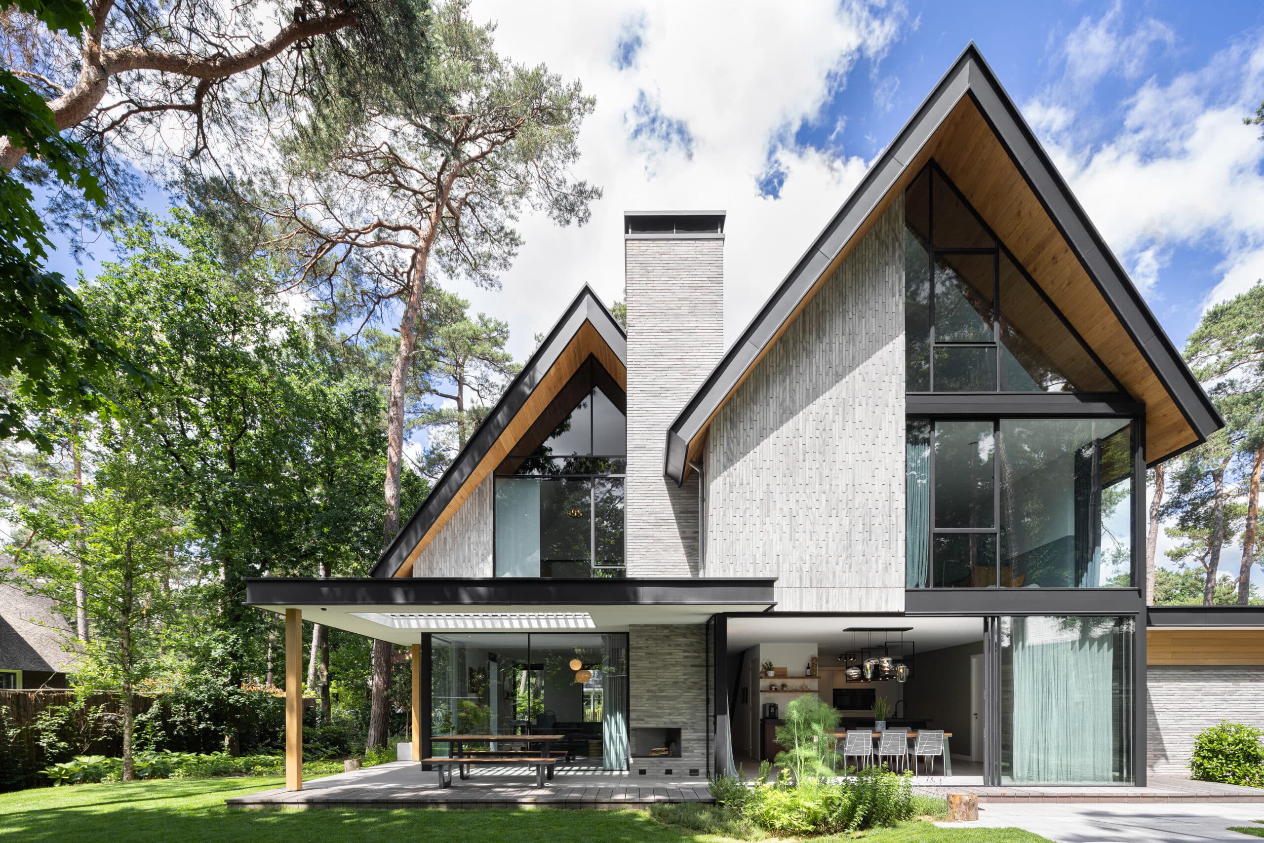Villa met grijze baksteengevels, grote raampartijen en houten dakaccenten
