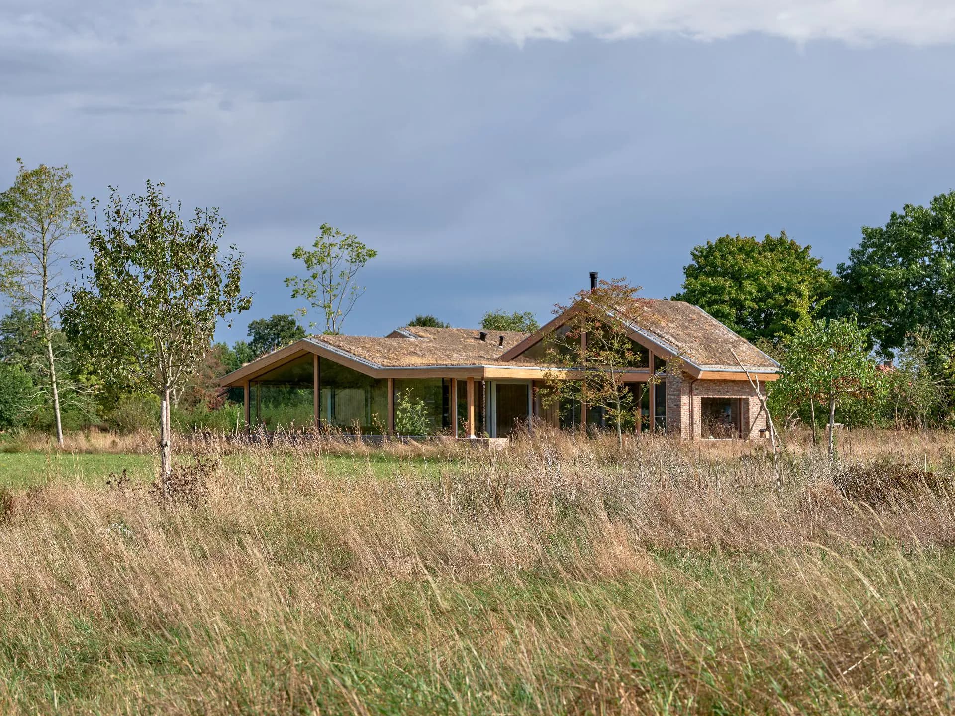 Bakstenen villa met houten afdak en rietkraag in landelijk veld