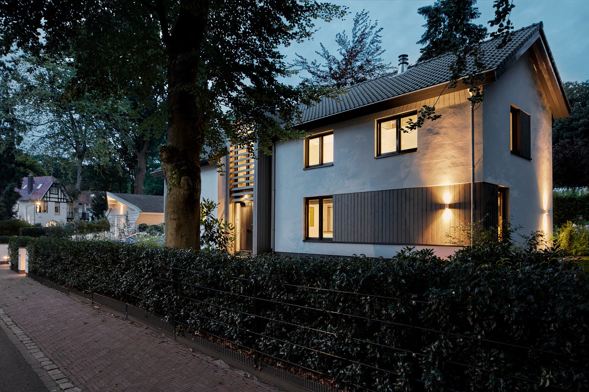 Moderne witte villa avondfoto met verlichte ramen en donker dak