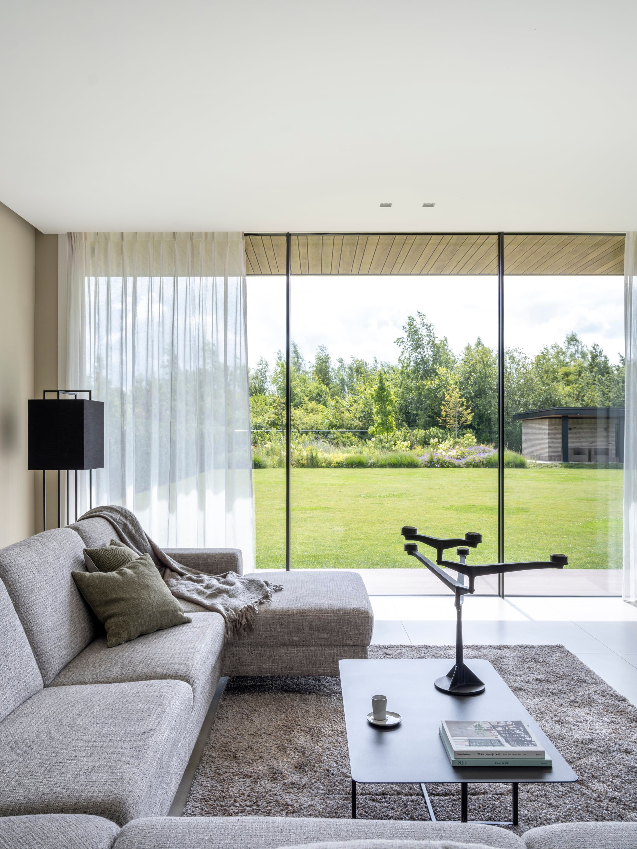Slaapkamer met houten plafonddetail en grote glazenwand naar tuin