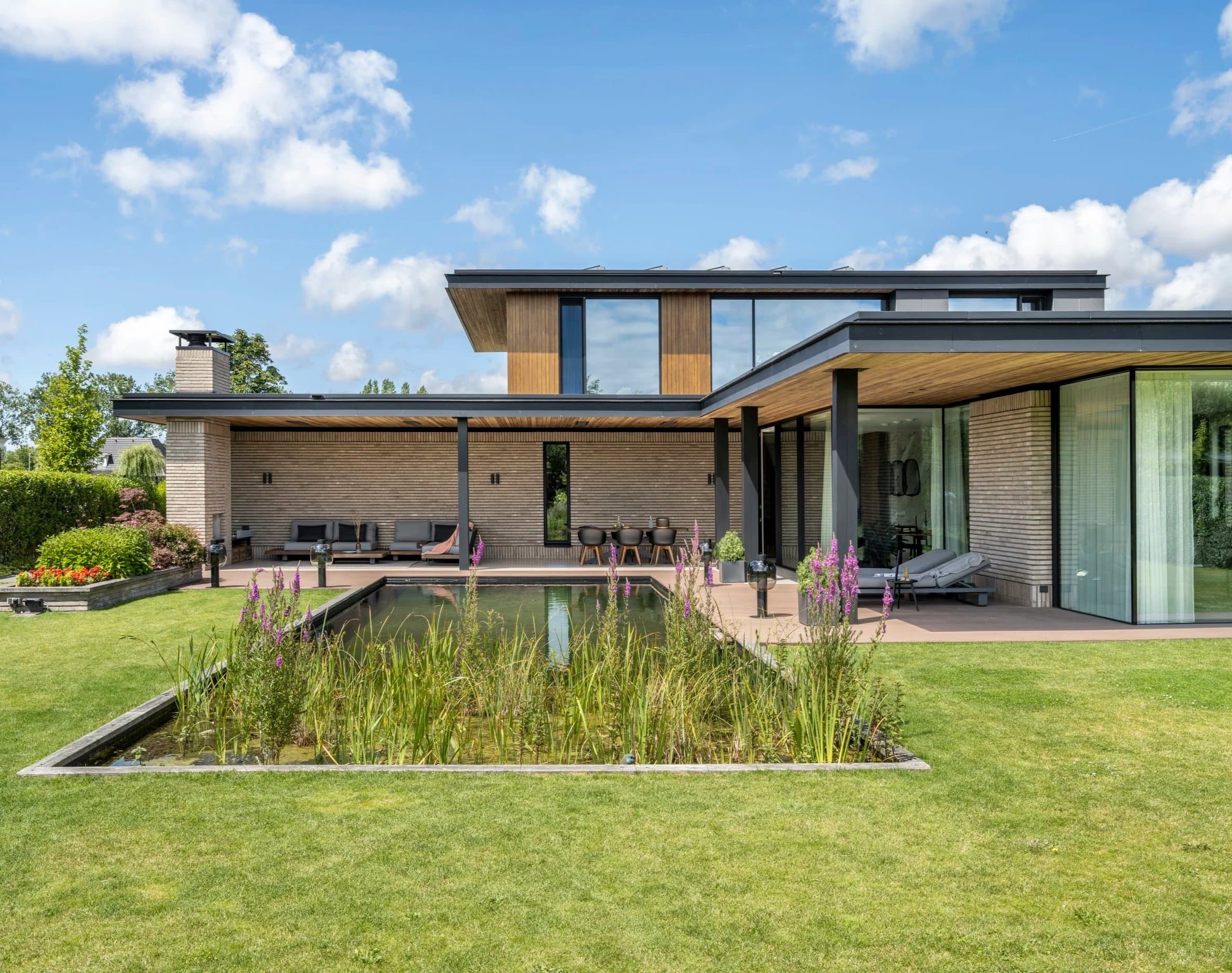 Hedendaagse woning met houtafwerking, terras en vijver in landschapstuin
