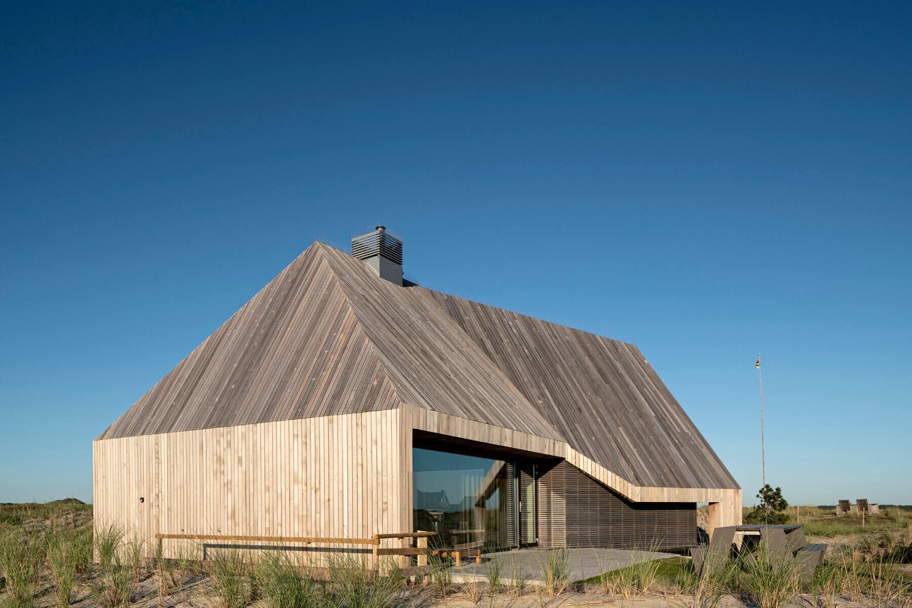 Minimale villa op duinen met bleek houtskeletwerk en gesloten voorgevel