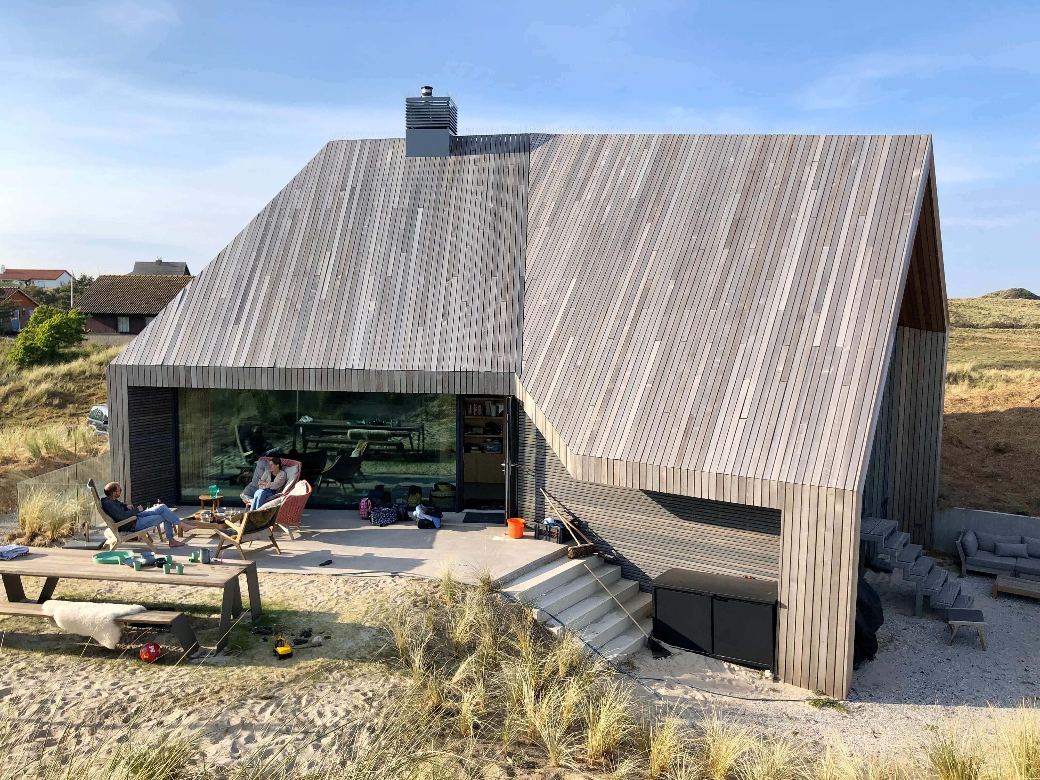 Moderne strandvilla met hellend golfplaten dak en uitkragende overkapping