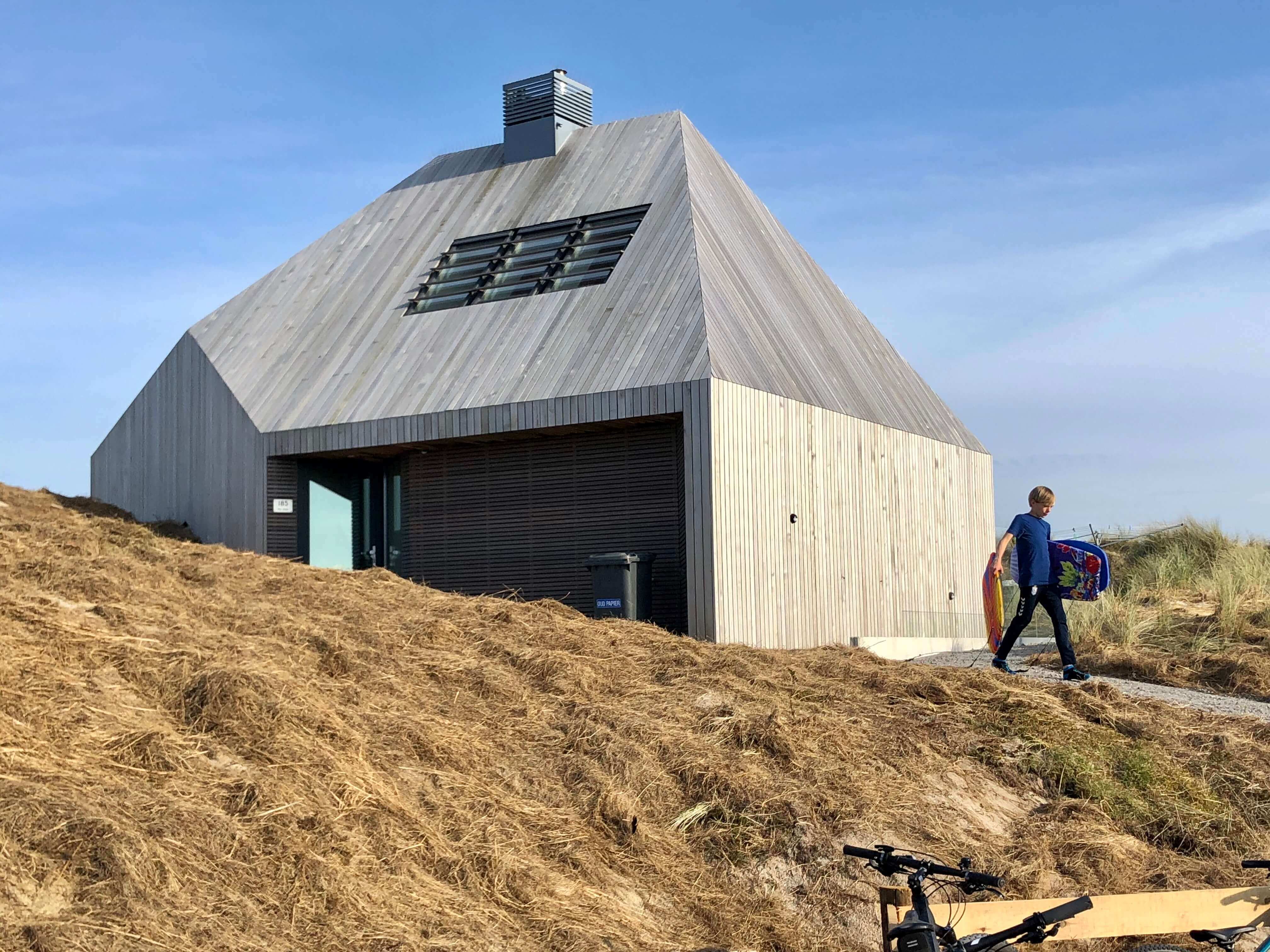 Moderne villa met grijswit golfplaten dak en grote raampartijen op strand