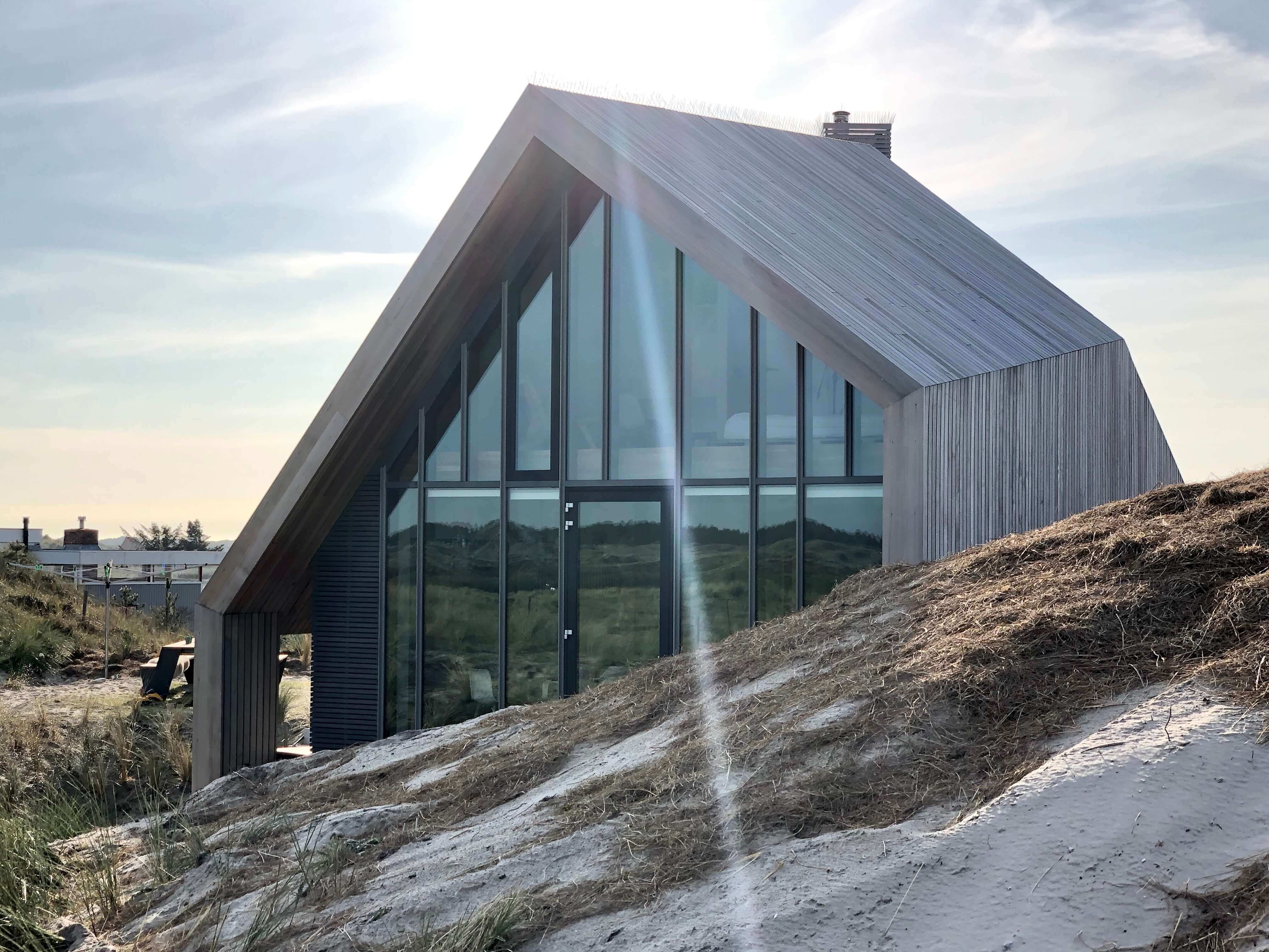 Minimalistische duinvilla met grijze metalen wanden en panoramische glazen zijde