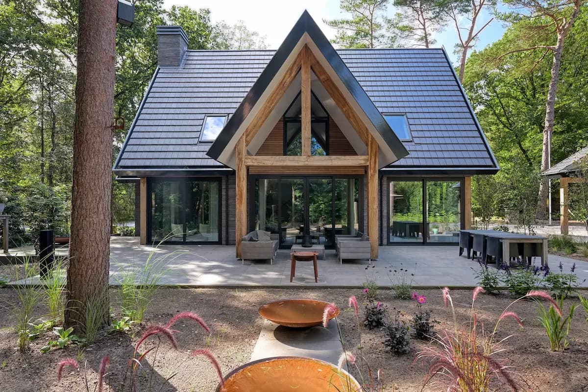 Modern A-frame house with dark roof and large glass sliding doors