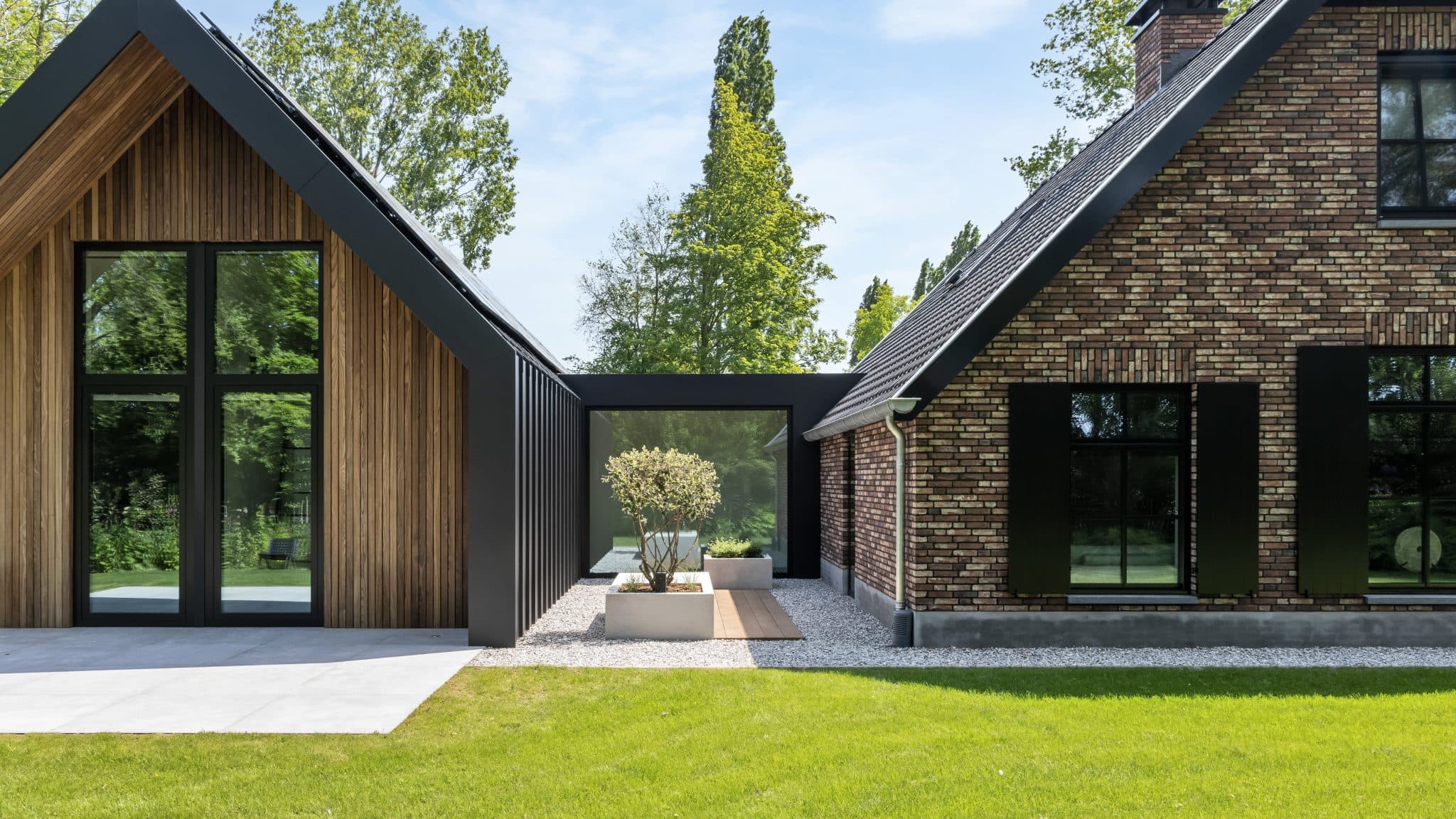 Rijtjeswoning met bakstenen zijgevel, houten voorgevel en zwarte deur