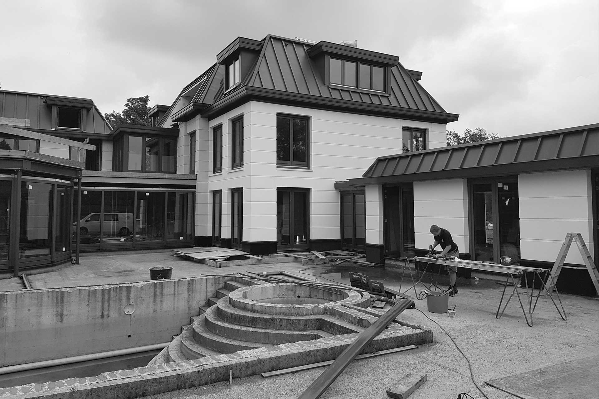 Witte villa onder constructie met betonnen vuurplaats en gereedschap