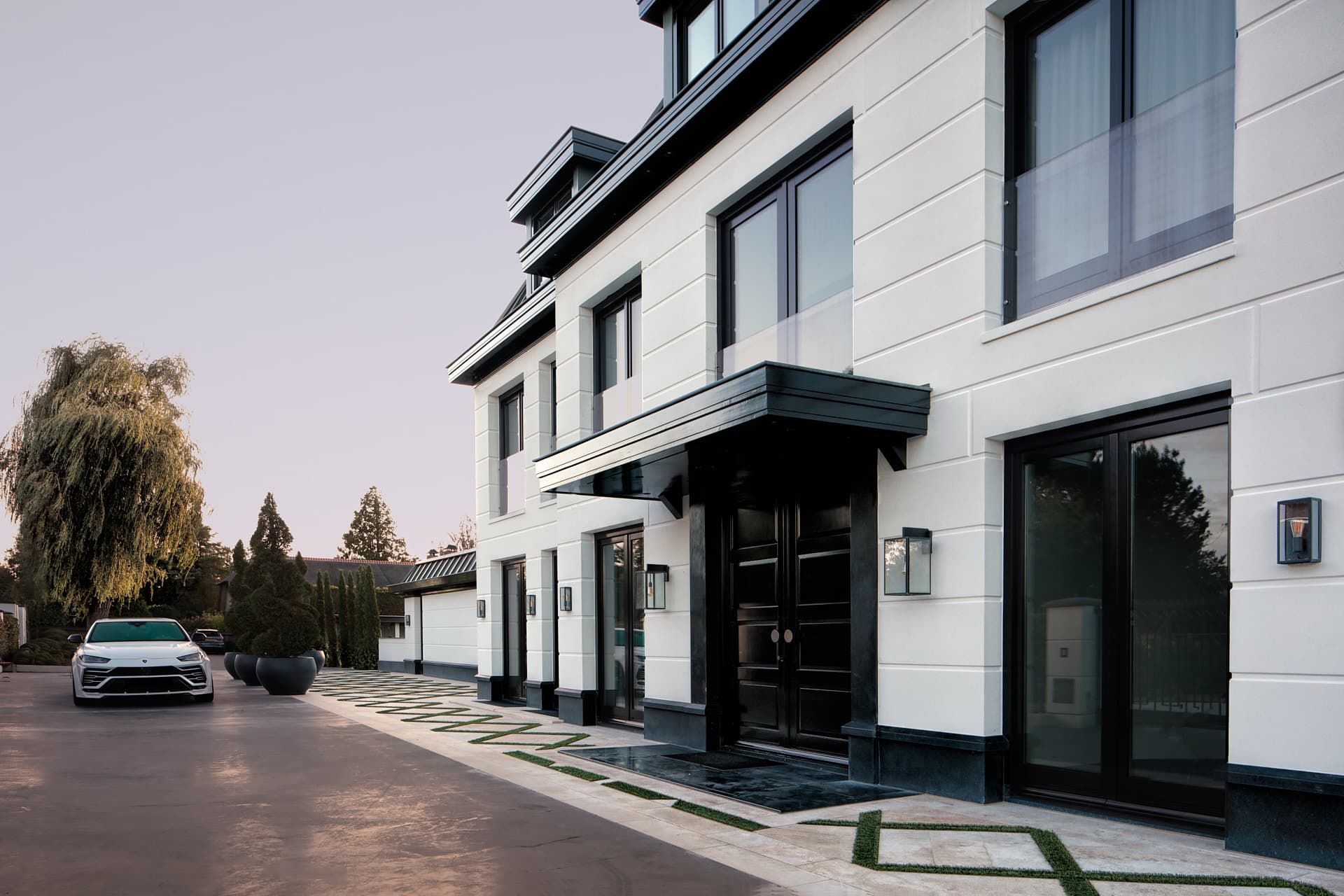 Moderne witte villa met zwarte details en aangelegde oprit met auto