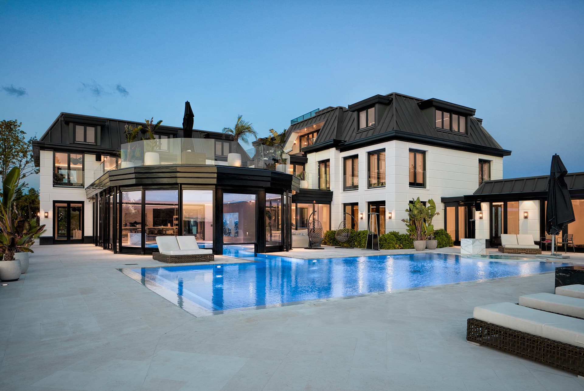 Moderne villa met zwembad, loungesets en geïntegreerde vuurplaats bij schemer