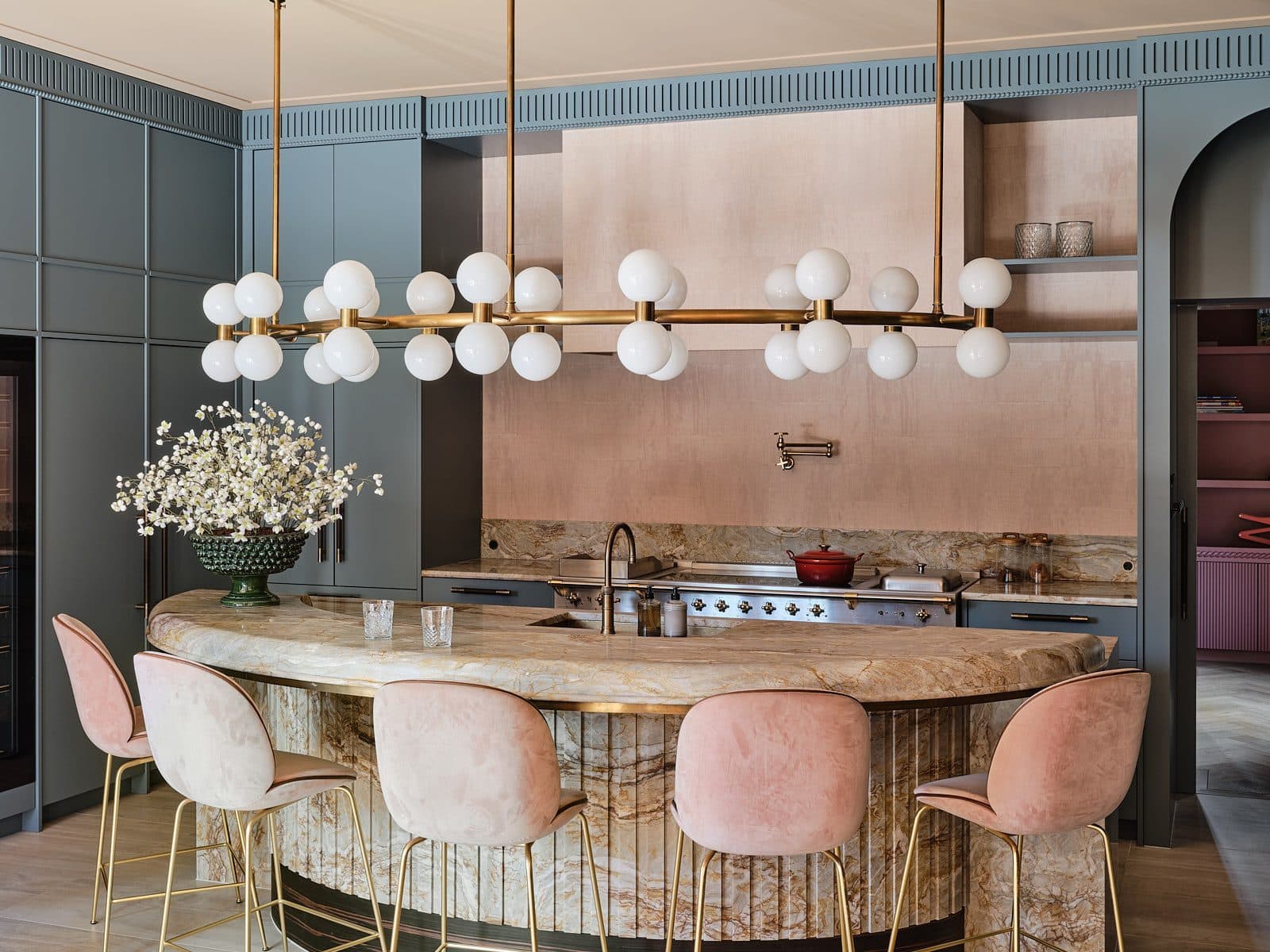 Keuken met travertijn eiland, marmeren backsplash en messing hanglamp