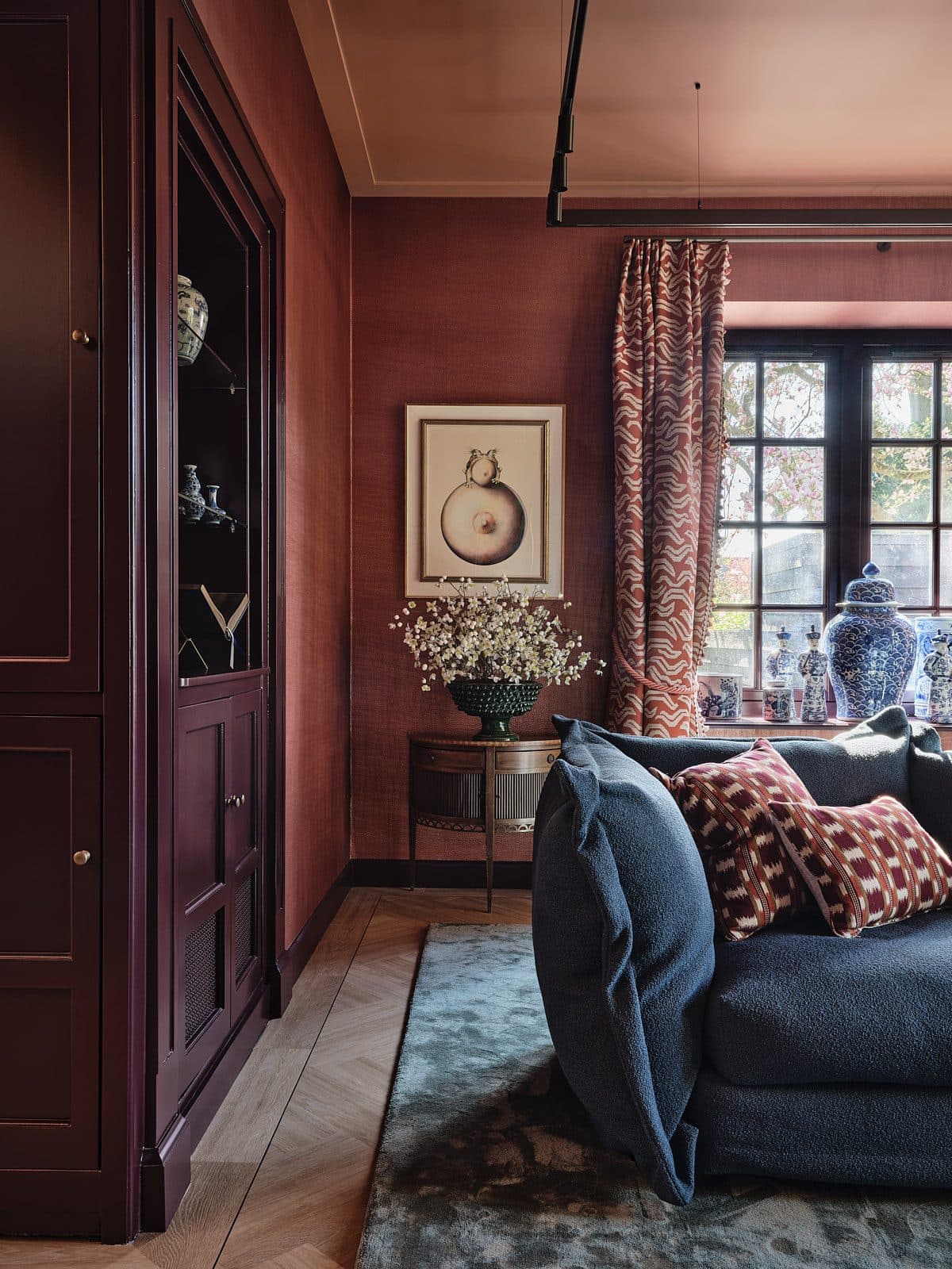 Woonkamer met terracotta muren, rood geruit behang en gemengde zitmeubelen