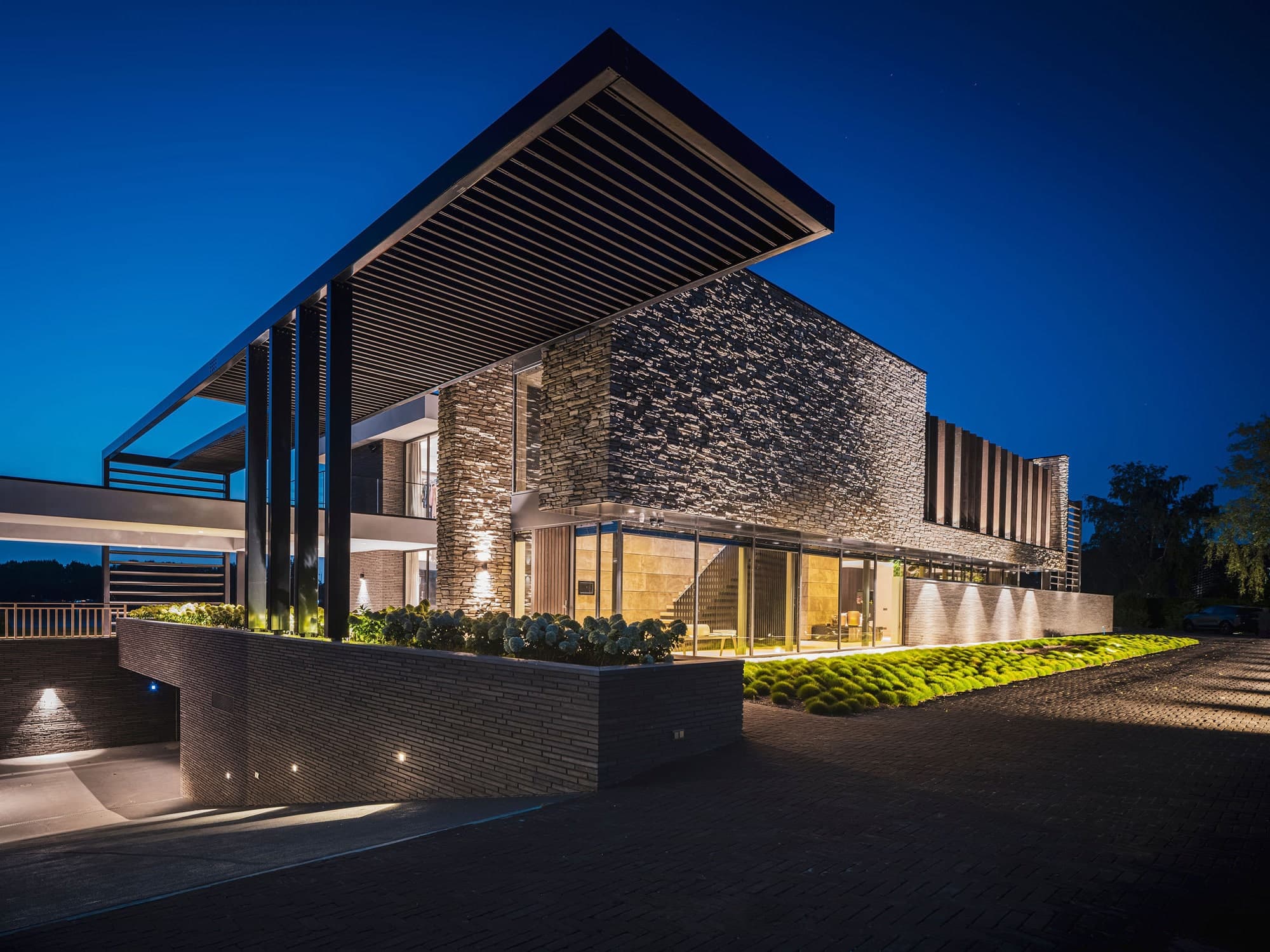 Moderne villa-gevel met zwart staal, grote raampartijen en terras met loungesets