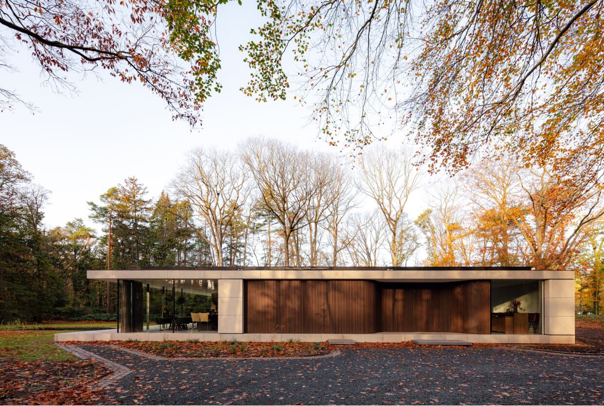 Moderne villa met houtbekleding en grote ramen, ingebouwd in bosrijke omgeving