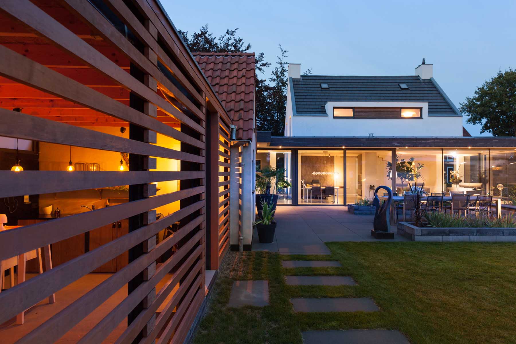 Tuinzijde moderne villa met houten dak-overstekking en volle glazing