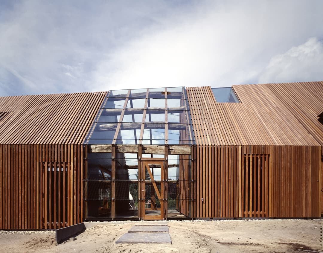 Moderne villa met houten gevelbekleding en glazen vooringang op zandpad