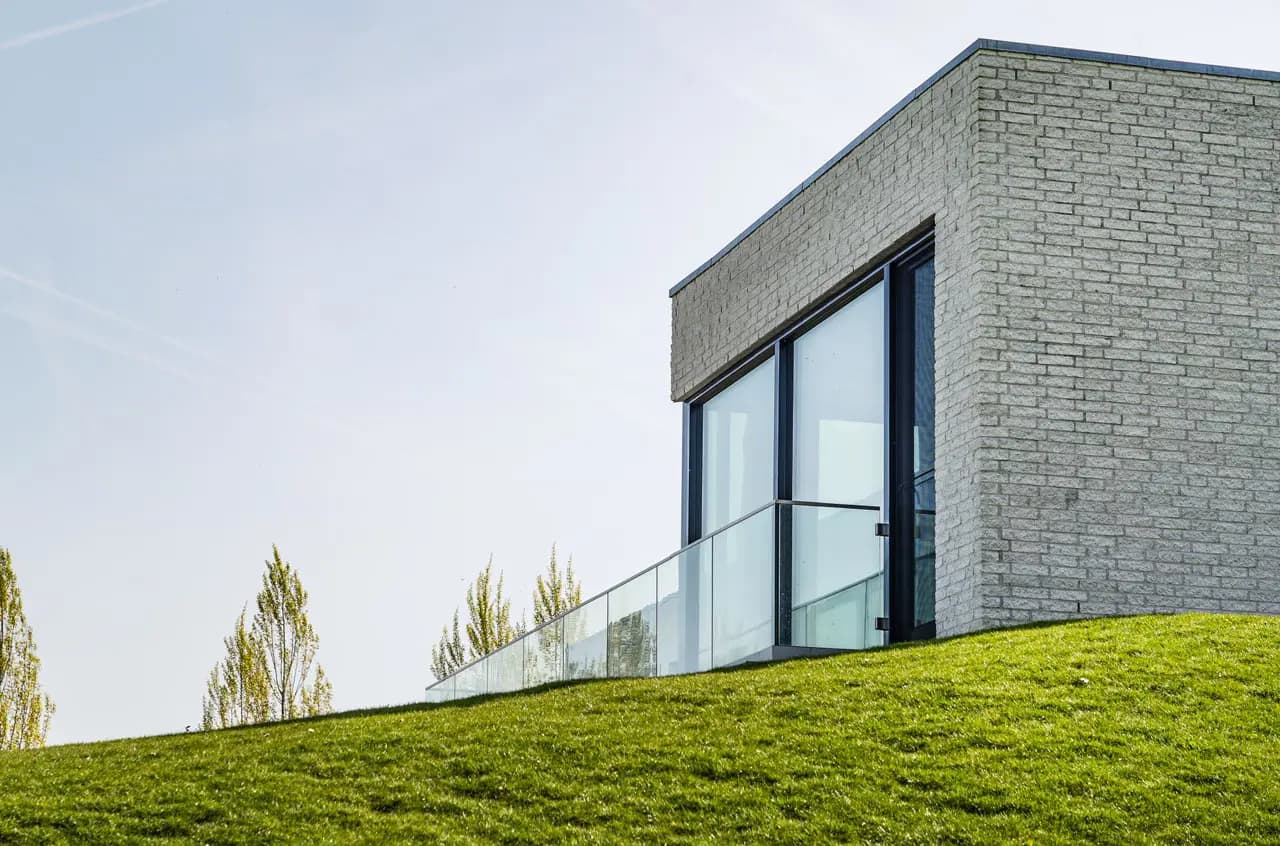 Moderne villavleugel met grijs metselwerk en zwart-framed glazen terrasdeuren