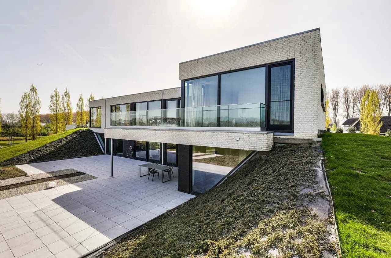Moderne villa met bakstenen gevel, uitkragende betonnen plaat en groene aarden wallen