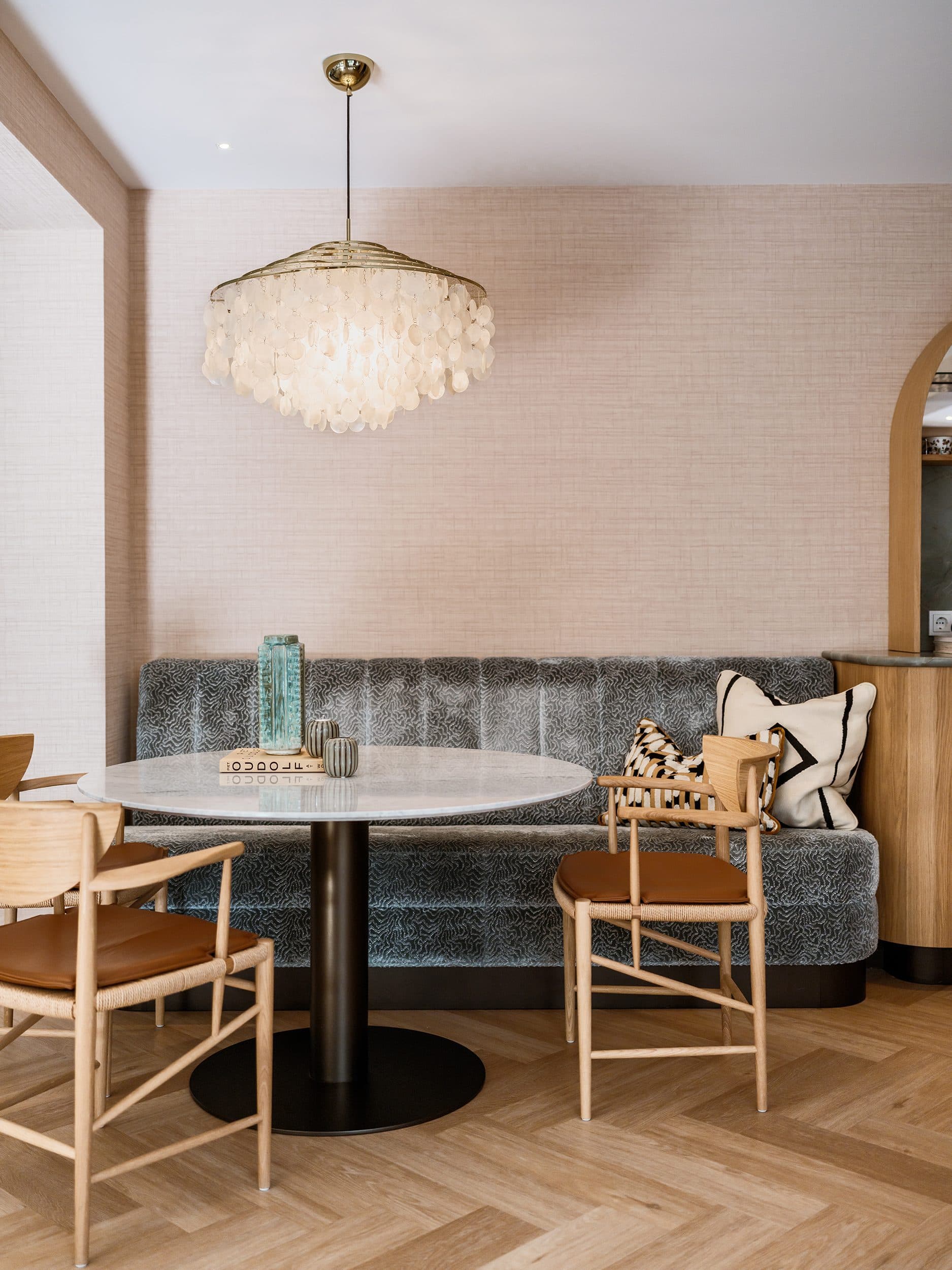 Eetkamer met ronde tafel, grijze zitbank en hanglamp met parelmoer