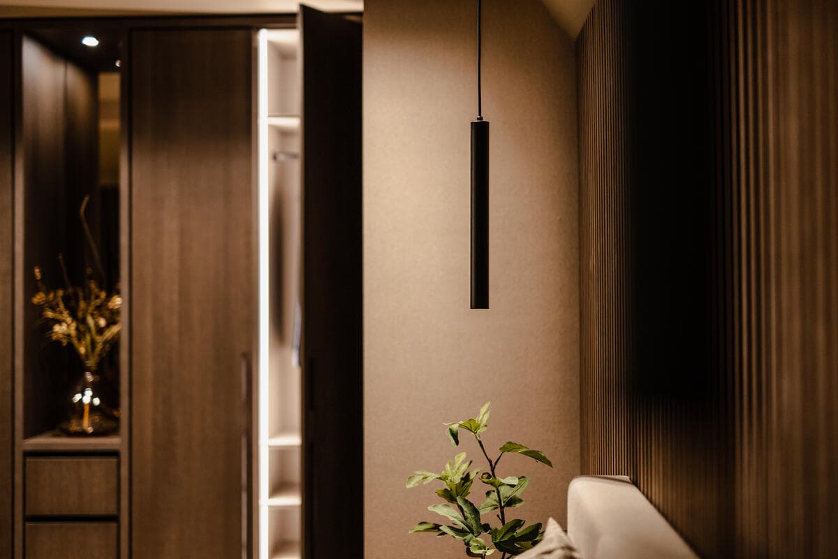 Garderobe met verlichte spiegelkast, donker hout en hangende verlichting
