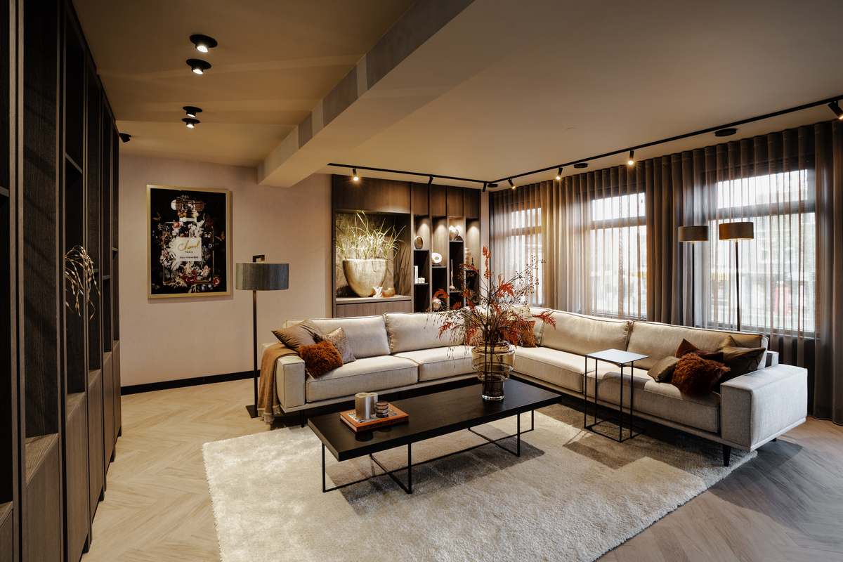 Woonkamer met beige hoeksalon, zwarte salontafel en gordijnen