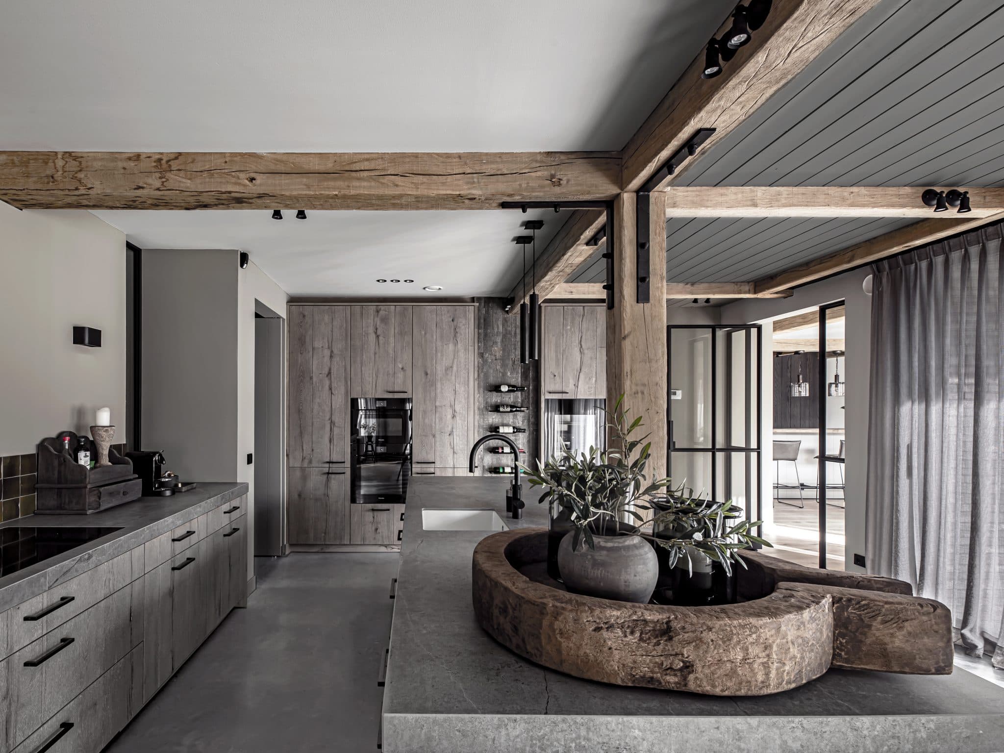 Moderne keuken met grijze houten kasten en ronde betonnen plantenbak