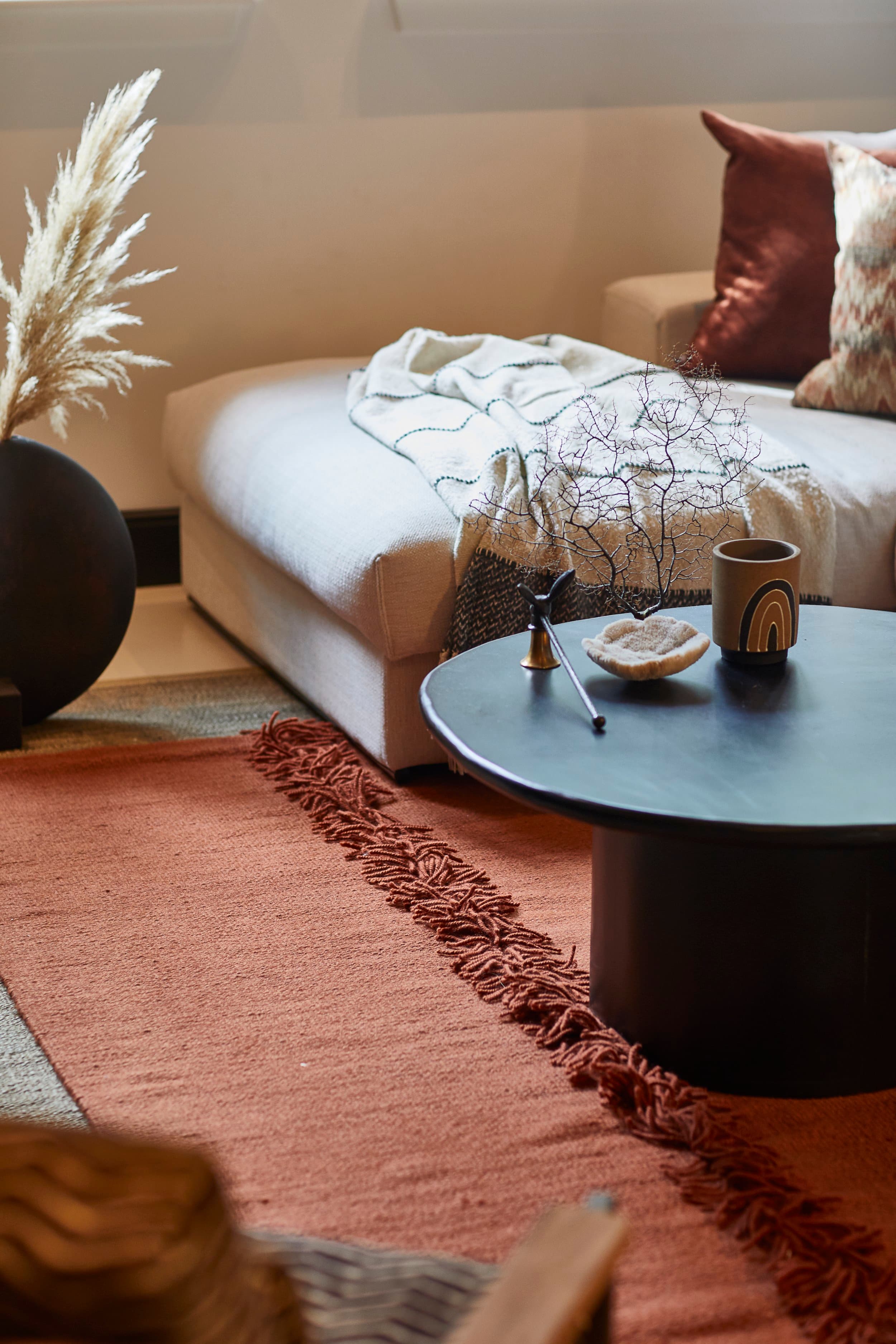 Zithoek met beige fauteuil, terra cotta tapijt en zwart tafeltje