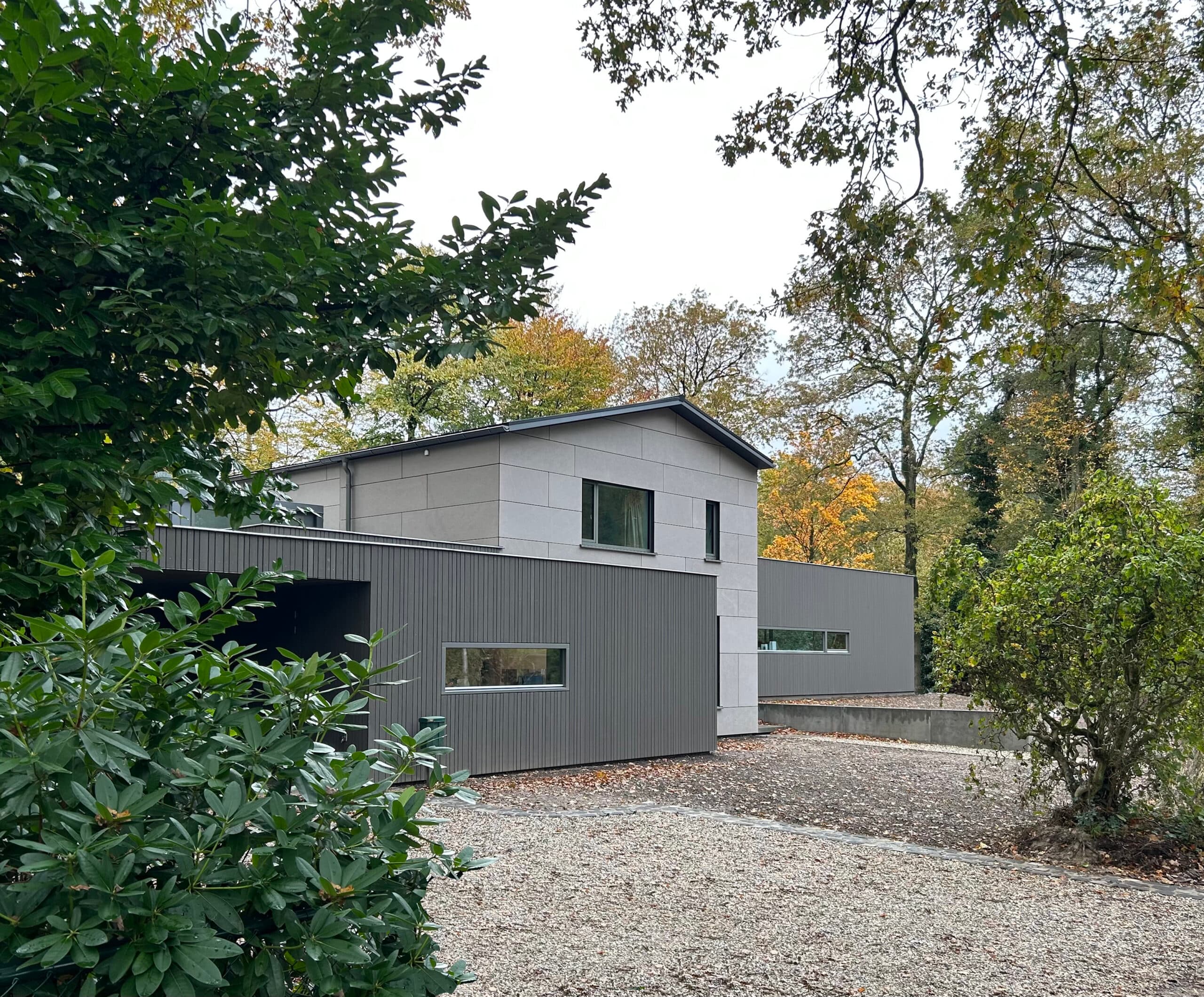 Halfopen woning met wit geveldeel en grijze golfplaten zijvleugel