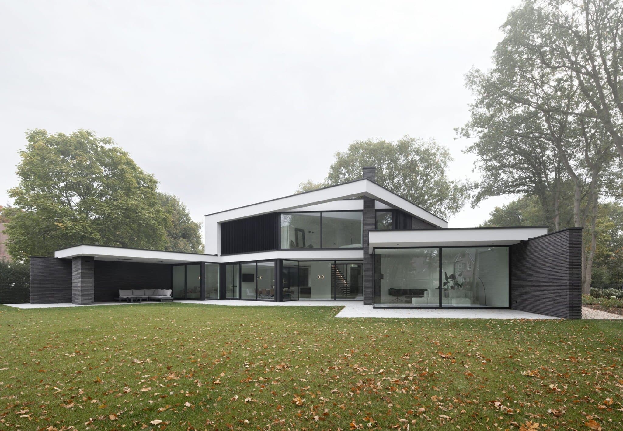 Moderne villa met donkergrijze baksteengevel, witte daklijsten en glazen puien