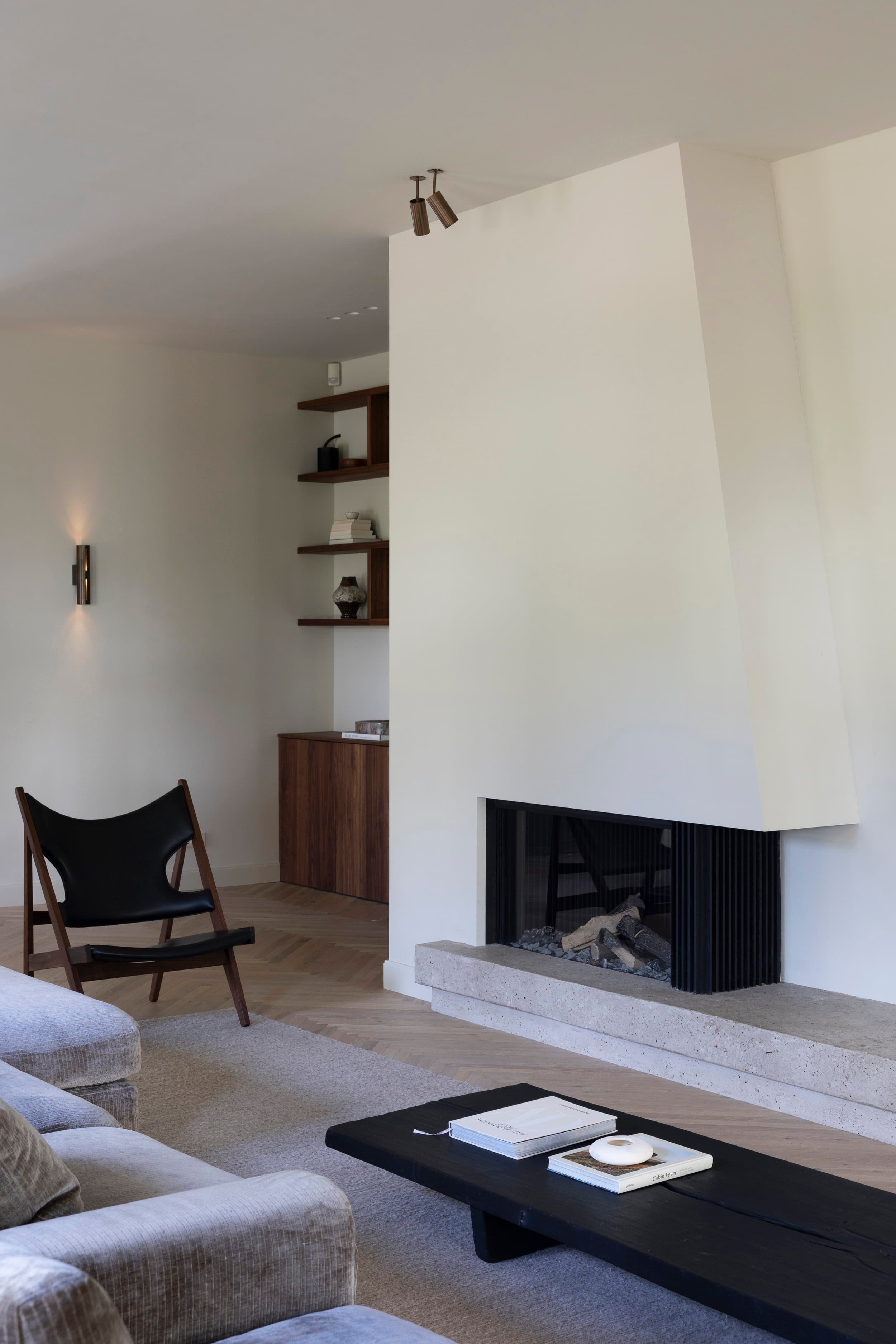 Zithoek met zwarte fauteuils, open haard en houten geschakelde wandplanken