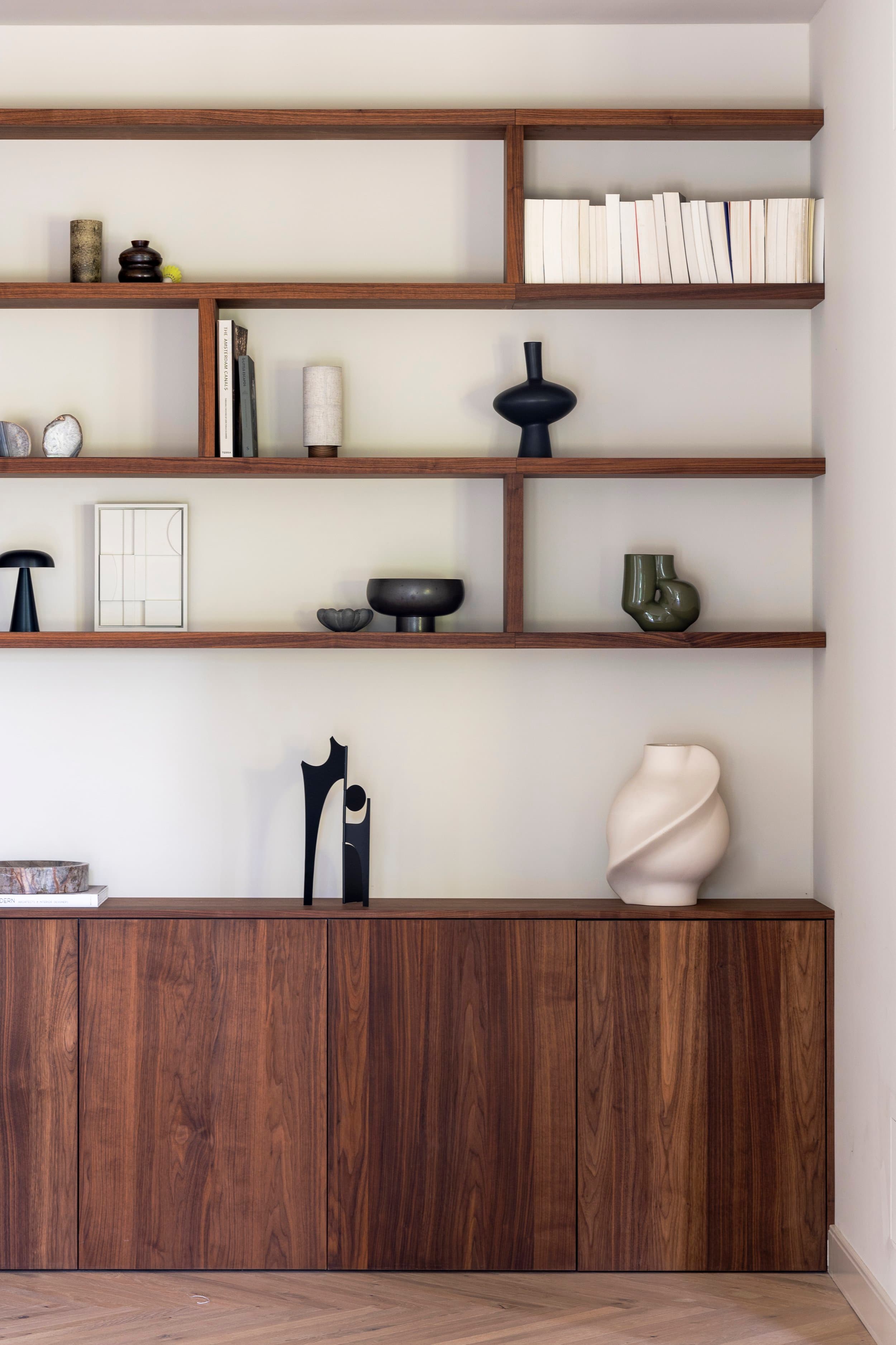 Wandkasten van donker hout met witte wanden en minimalistisch ingerichte planken