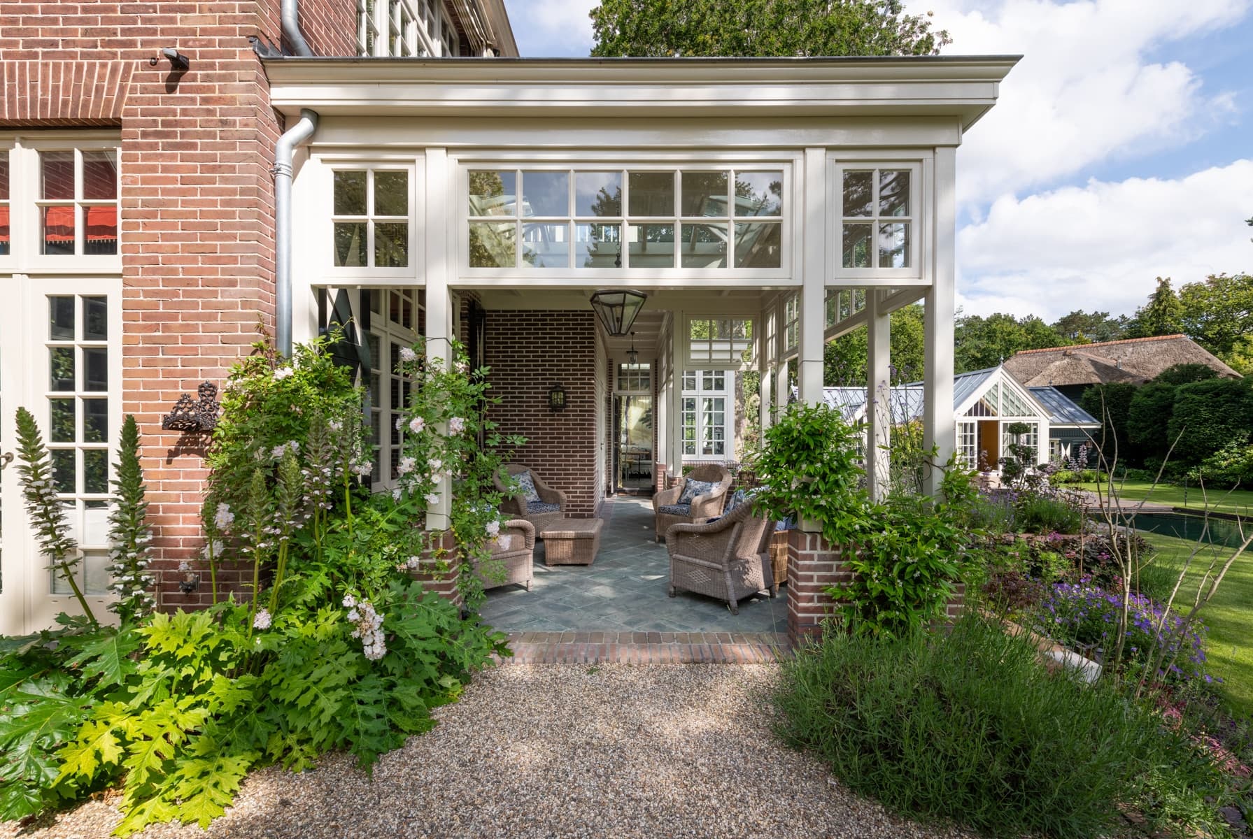 Moderne tuinpaviljoen met rietkap, blanke houten frames en reflectievijver