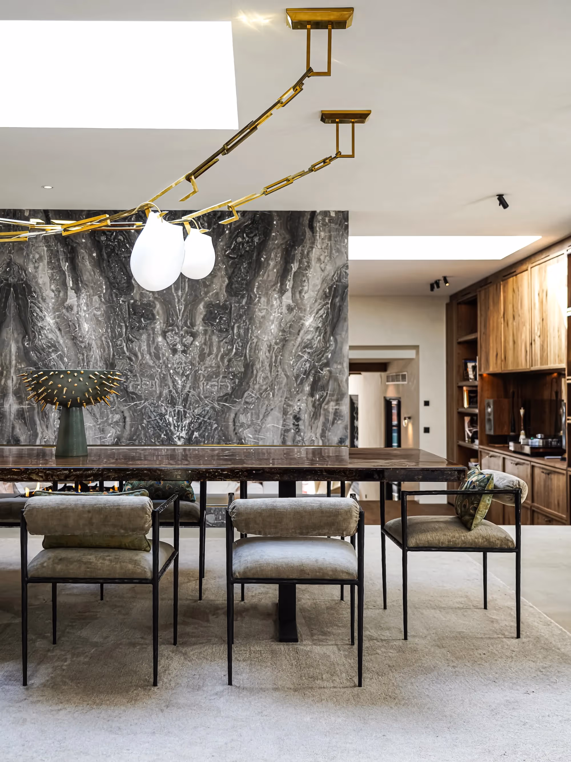 Eetkamer met grijze marmeren wand en messing hanglamp