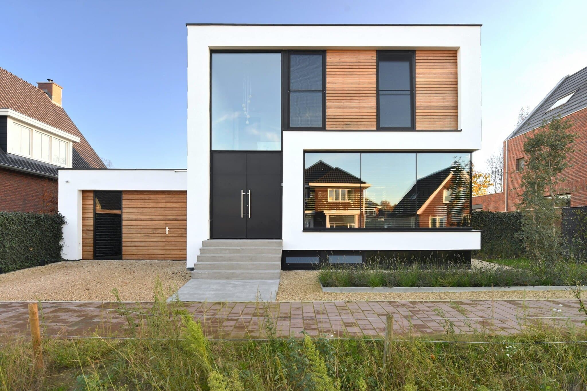 Hedendaagse woning met houten accenten, brede ingang en kasseienoprit