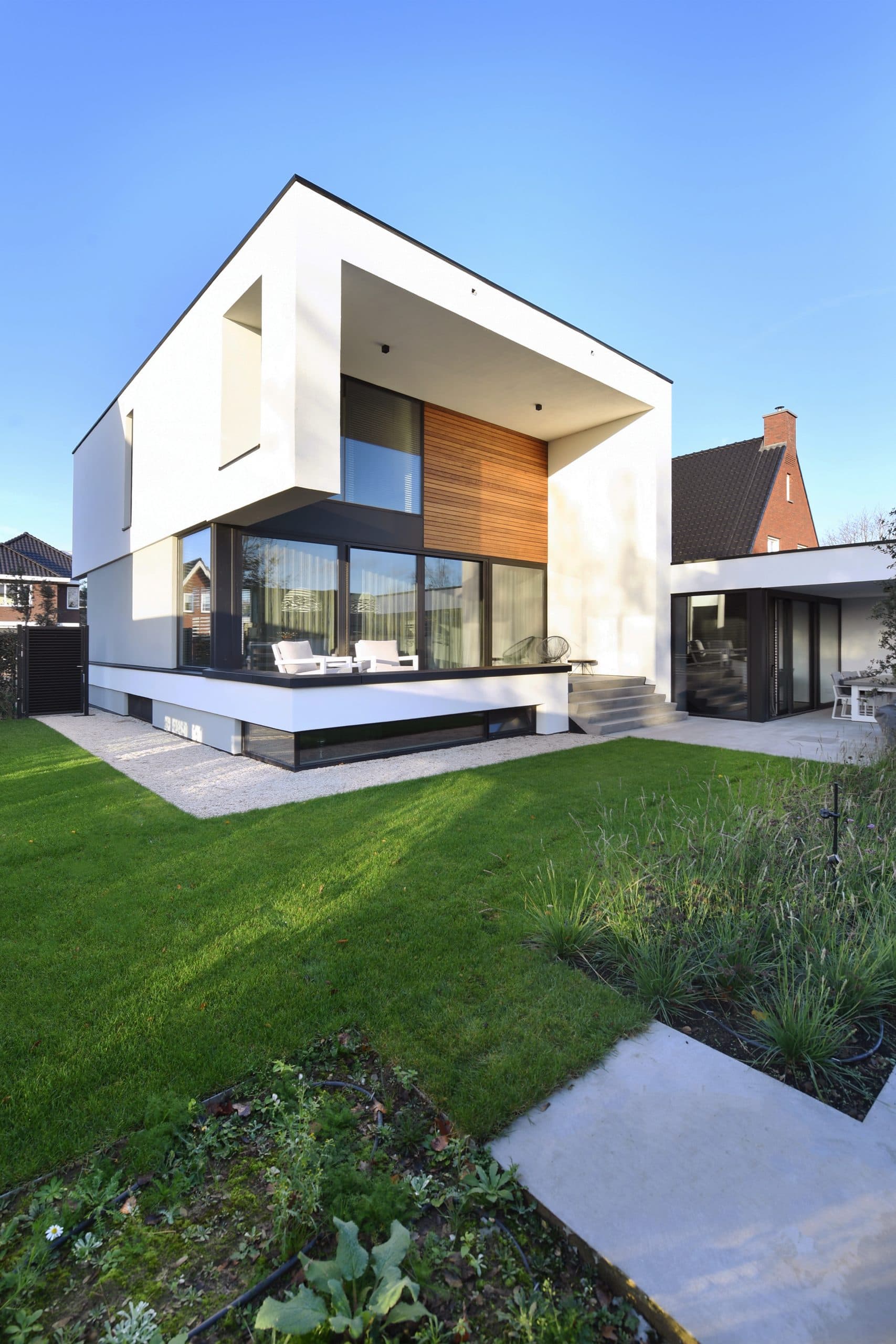 Wit gestukt modern huis met zwarte kozijnen en betonnen platformzockel