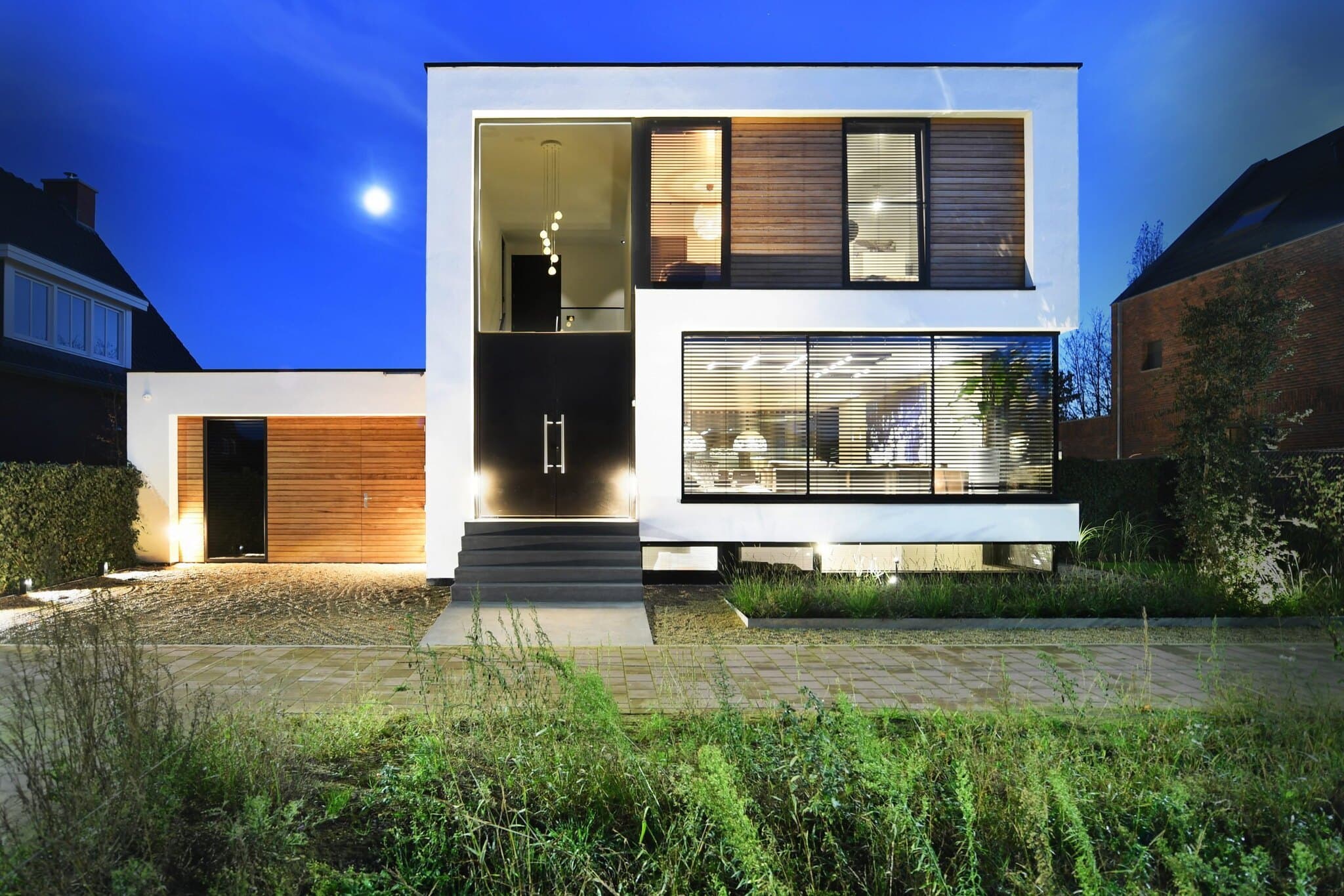 Hedendaagse villa met witte gevel, houten details en kasseienpad