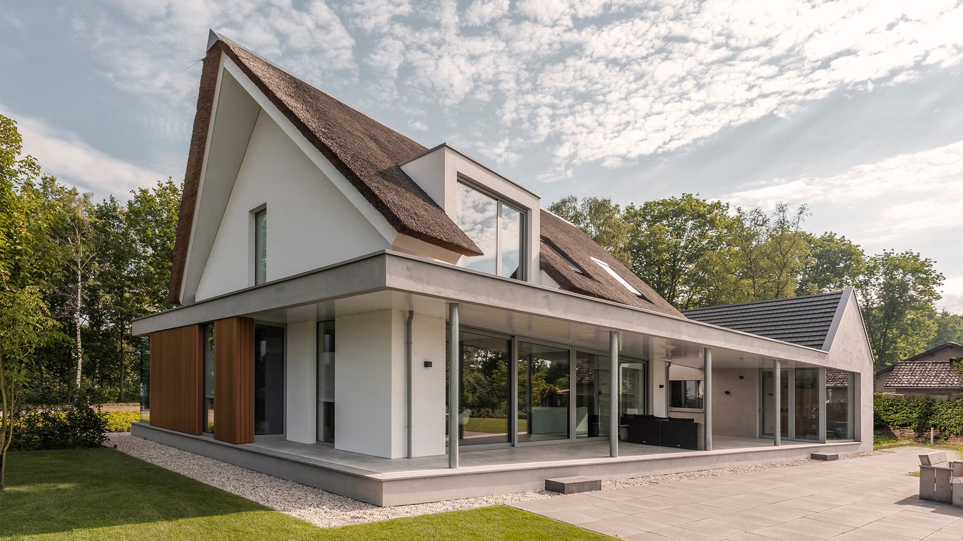 Rietgedekte villa met grote glazen hoekpuien, houten en witte gevelbekleding