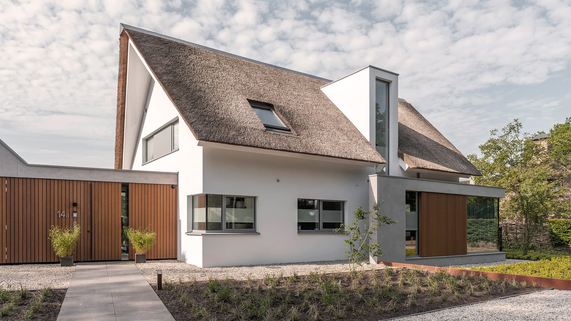 Moderne villa met rietgedekte daken, houten gevelbekleding, grote glazen puien