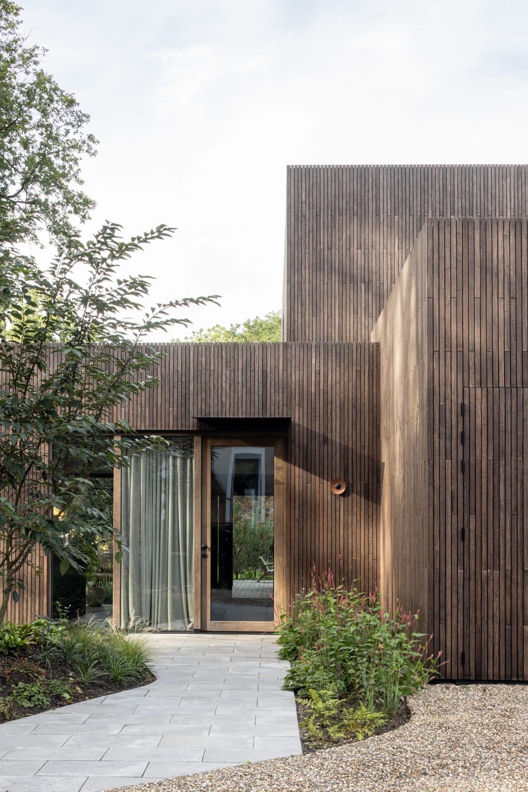 Ingang moderne villa met houten lamellen en tuin
