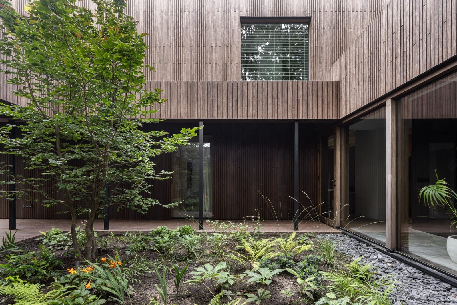Zijkant moderne villa met houten gevel en glaswanden
