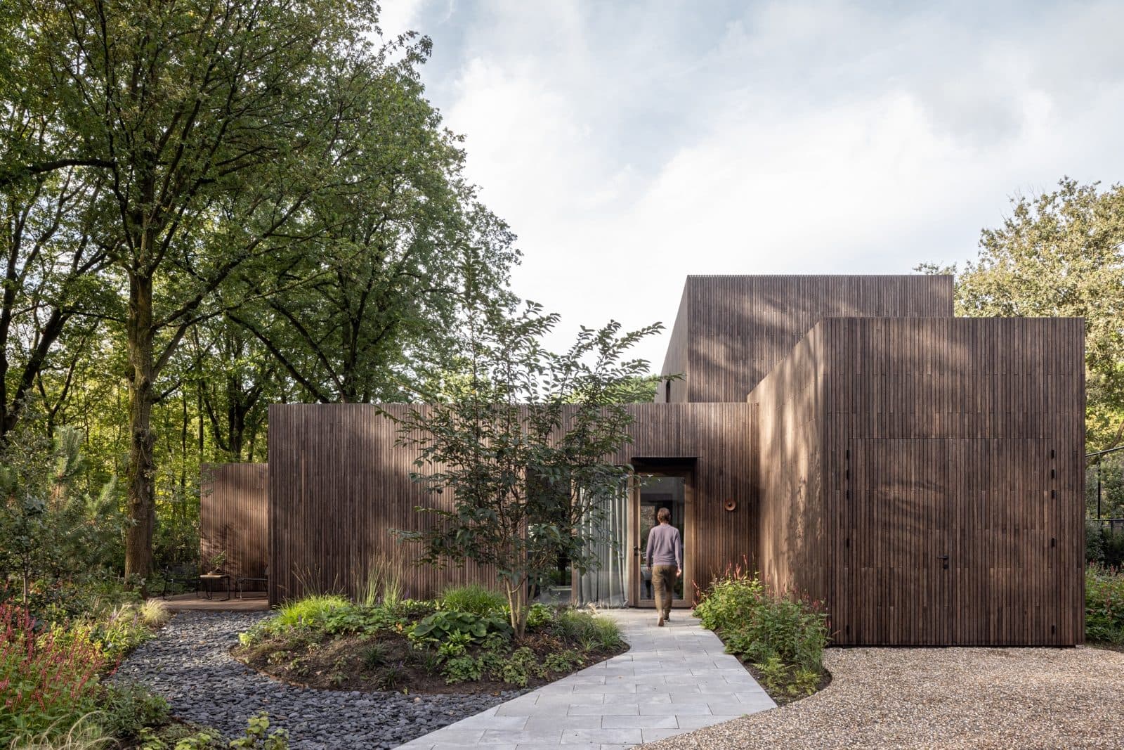 Entreepad naar moderne villa tussen bosrijke omgeving