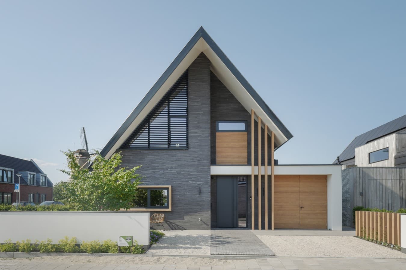 Frontaanzicht moderne villa, grijze bakstenen gevel en houten details